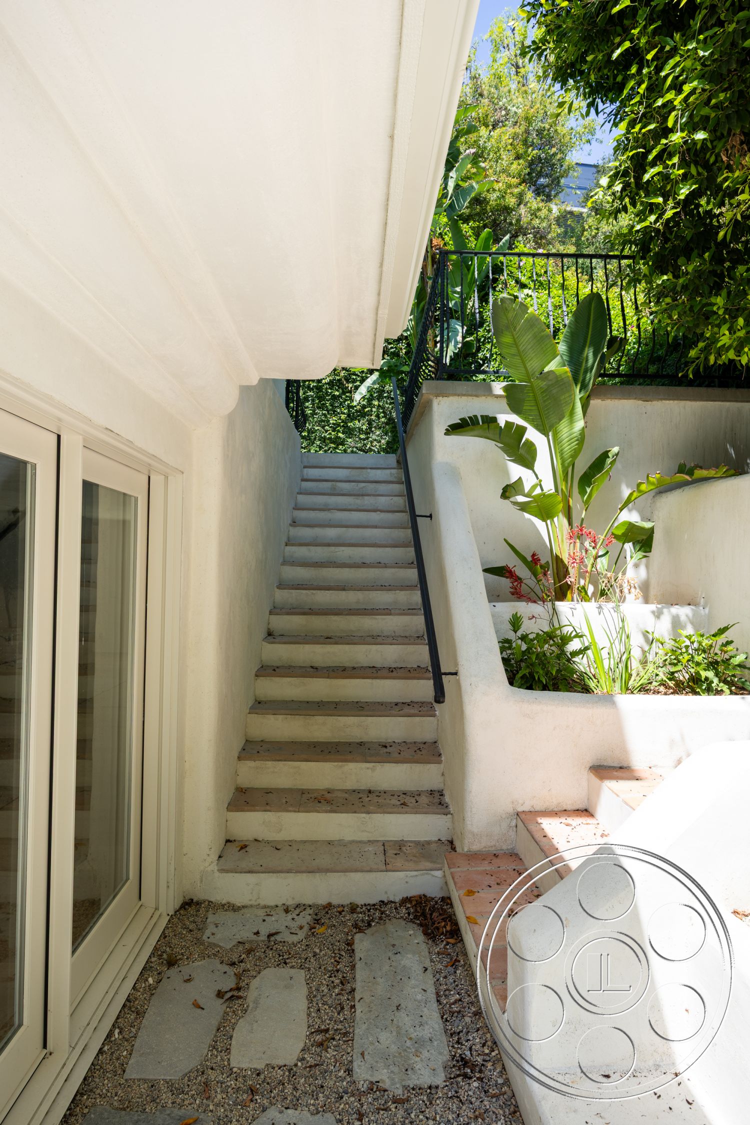 Medit 168 - exterior, textured wall finish, metal railing, concrete stairs, brick patio, stone pathway, garden area, white plaster walls, landscaped garden with tropical plants, step-up design