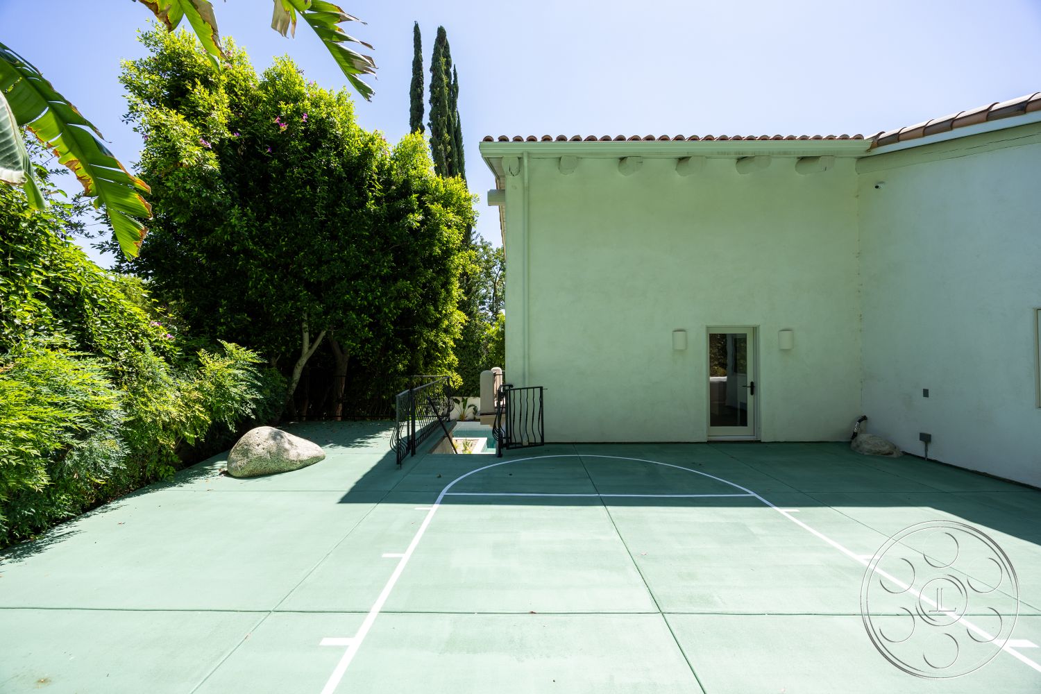 Medit 168 - exterior, tall cypress trees, stucco walls, flat roof design, landscaped garden area, outdoor patio area, green concrete basketball court, rock garden boulders, white modern house