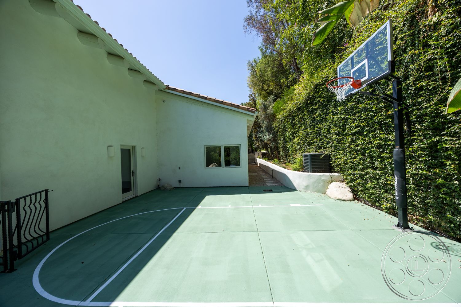 Medit 168 - exterior, large window, concrete wall, garden path, flat roof design, white painted walls, surrounding lush greenery, green basketball court paving, gated access area, fiberglass basketball hoop