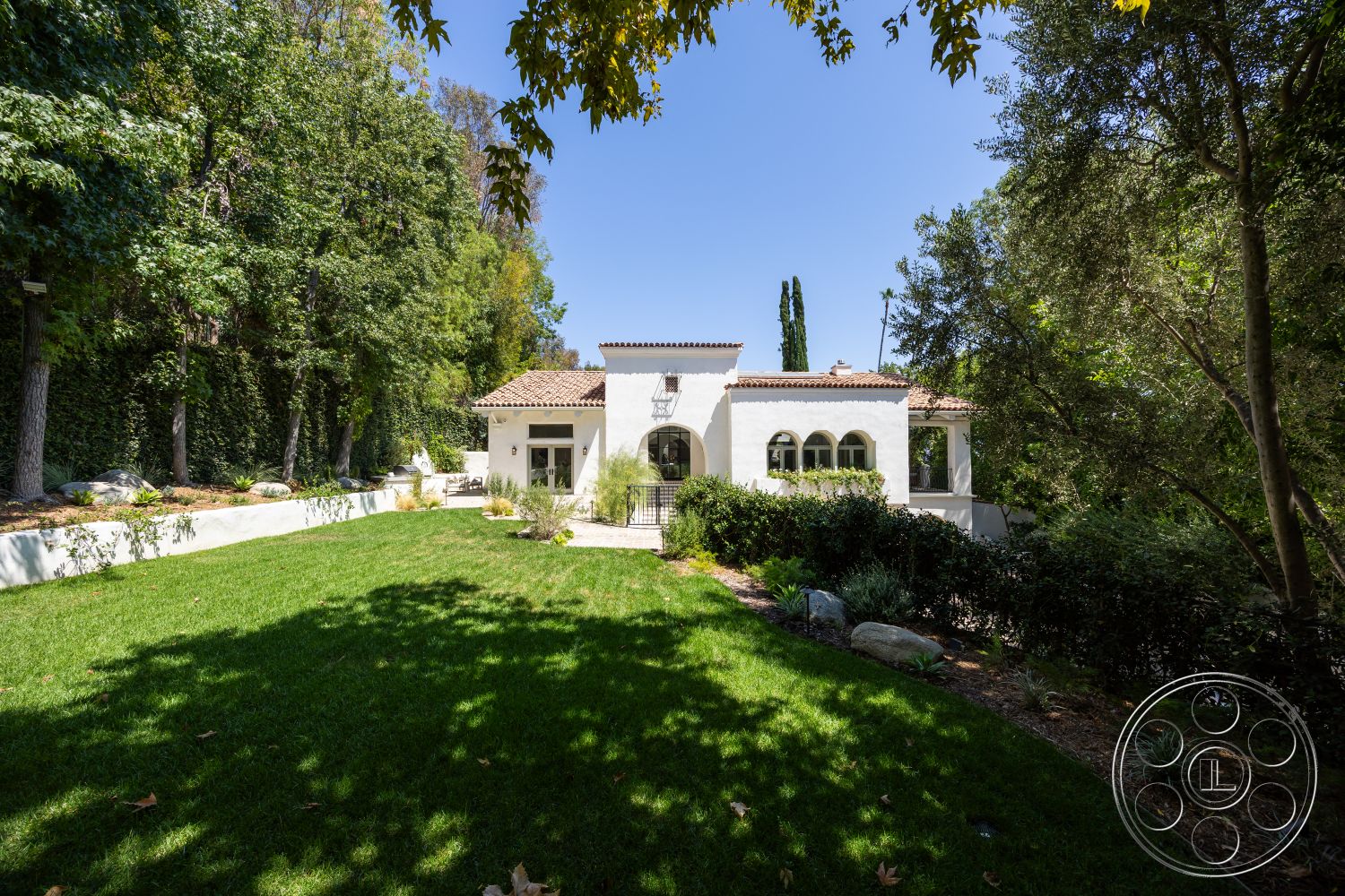 Medit 168 - exterior, landscaped garden, manicured lawn, terracotta roof tiles, stucco walls, arched doorways, elevated setting, arched windows, surrounded by trees, Mediterranean architectural style, two-story home, pathway stones, native shrubs