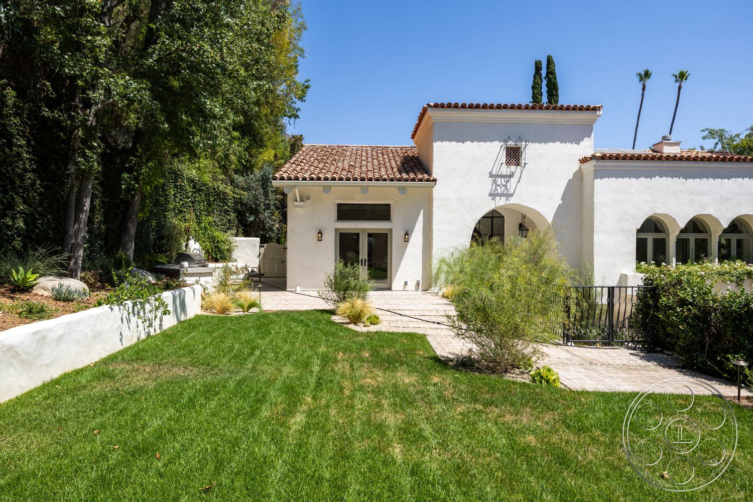 Medit 168 - exterior, landscaped garden, lawn, stucco walls, Spanish tile roof, arched windows, tall palm trees, ornamental shrubs, outdoor lighting fixtures, paved stone walkway, natural stone garden accents, modern patio railing, pedestrian gate