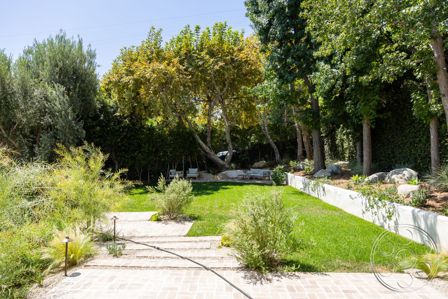 Medit 168 - exterior, landscaped garden, mature trees, lush green lawn, gravel pathways, concrete stepping stones, low-maintenance shrubs, decorative stone border, tropical plant accents, wooden patio seating area