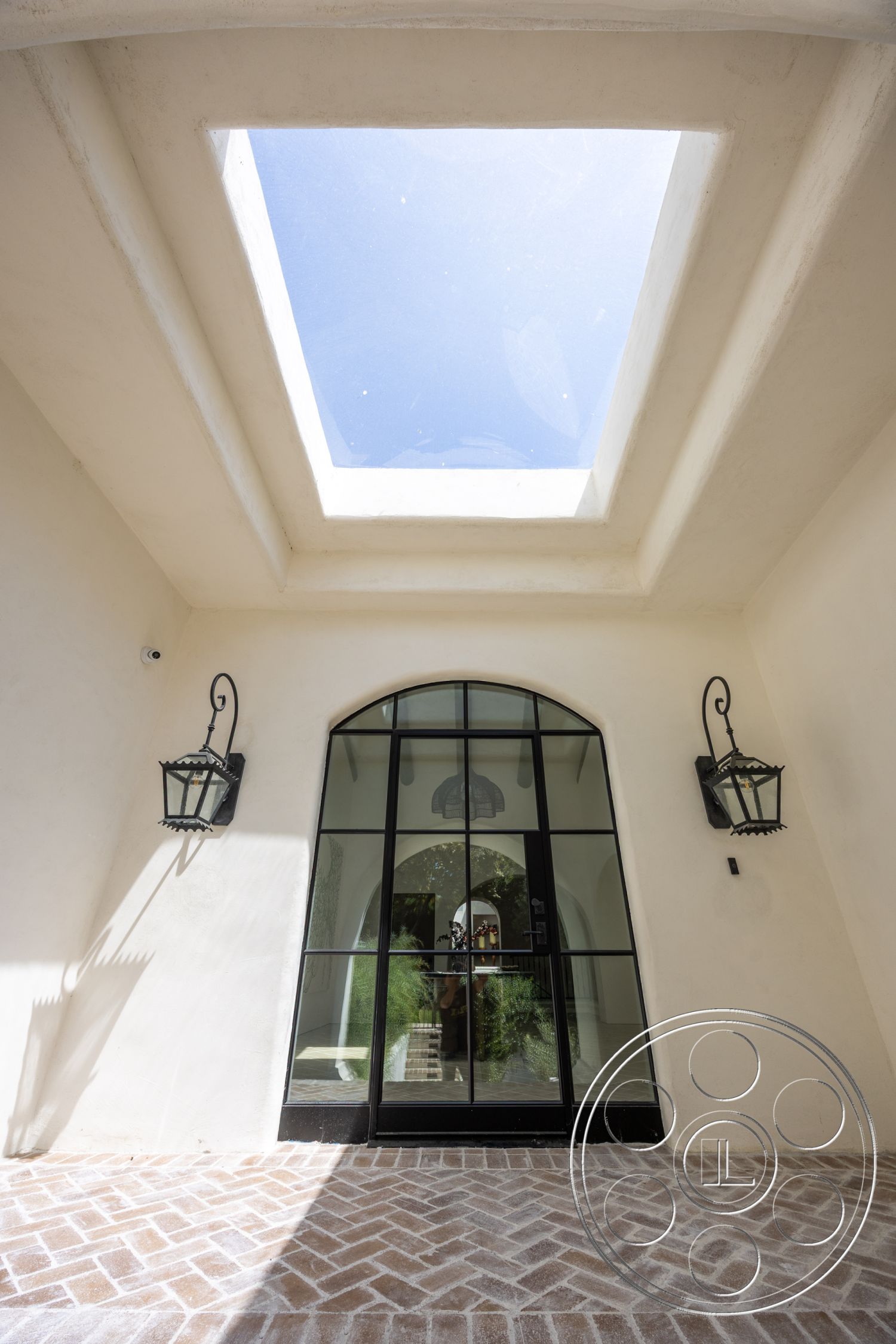 Medit 168 - exterior, herringbone pattern flooring, skylight, arched doorway, exposed light fixtures, terracotta tile flooring, white plaster walls, curved ceiling detail, black framed glass entrance