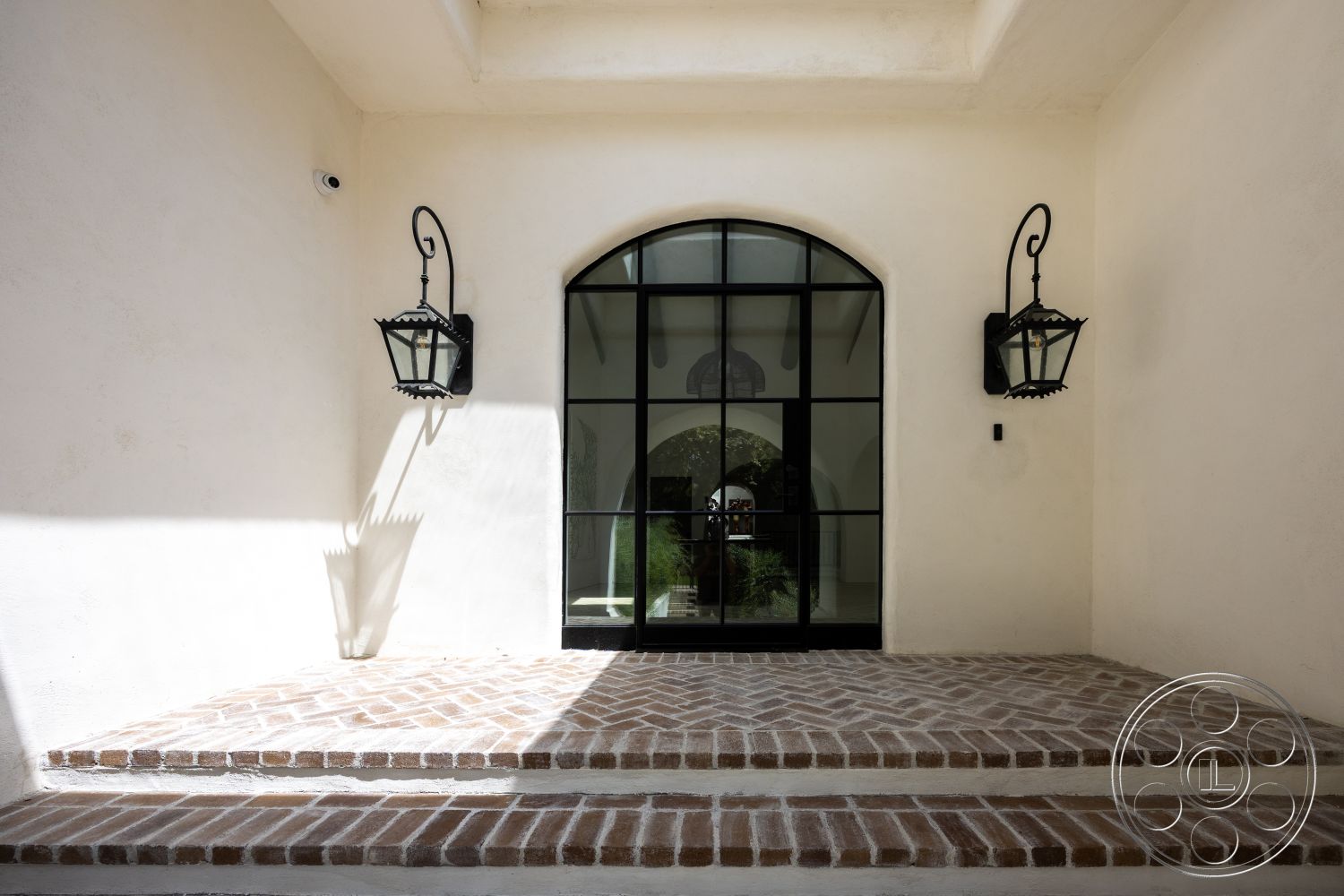 Medit 168 - neutral color palette, exterior, vaulted ceiling, textured plaster walls, arched doorway, brick patio flooring, black metal wall sconces, steel framed glass door