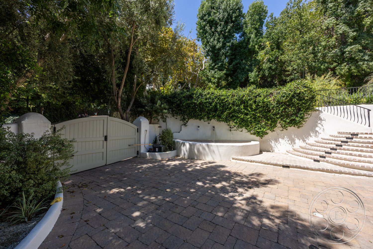 Medit 168 - exterior, paved driveway, lush greenery, outdoor seating area, mature trees, garden landscaping, decorative railing, stepped pathway, stucco wall, curved stone wall, wooden garden gate, interlocking stone pavers