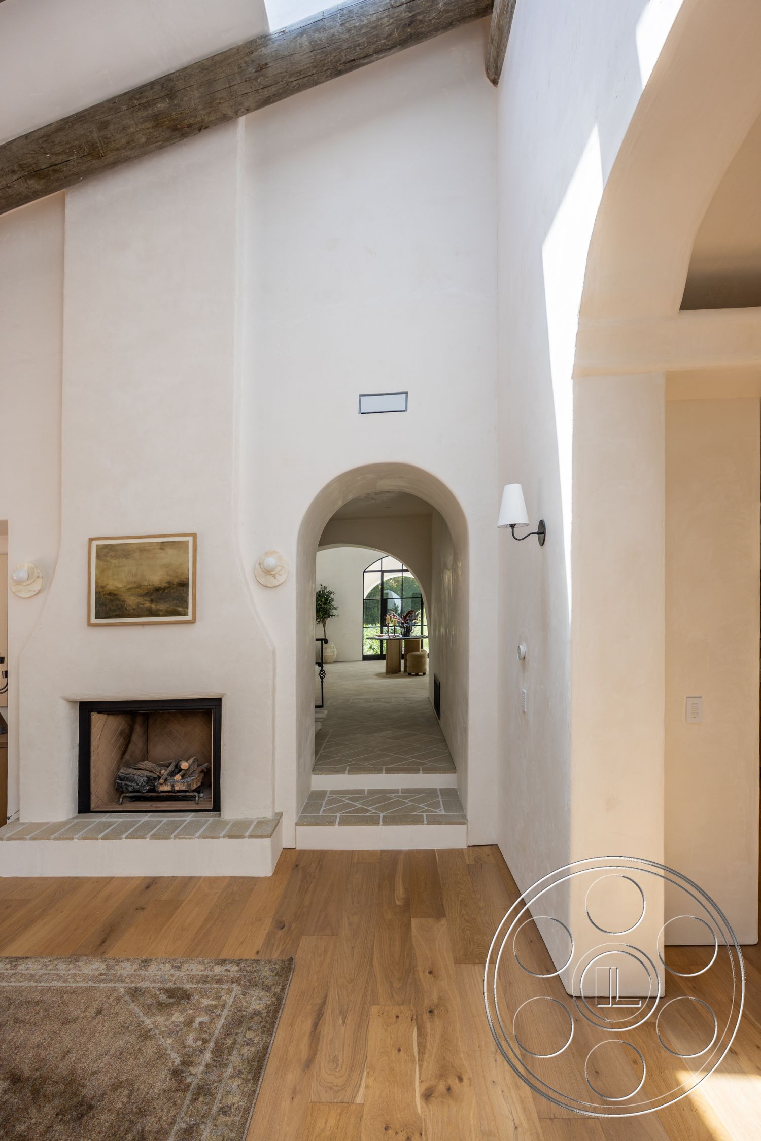 Medit 168 - open floor plan, arched doorways, modern rustic style, natural light from windows, textured wall treatment, geometric tile flooring, exposed wood ceiling beams, stone fireplace surround, oak hardwood flooring, plastered wall finish, minimalistic wall art