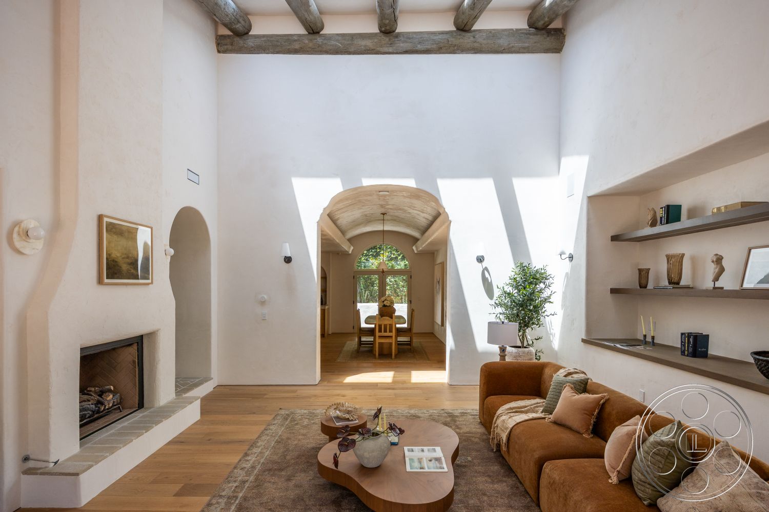 Medit 168 - neutral color palette, hardwood flooring, cozy seating area, arched doorways, textured plaster walls, exposed wood ceiling beams, natural light through large windows, built-in shelving units, stone fireplace surround, curved ceiling detail, modern living room layout, earthy decor accents