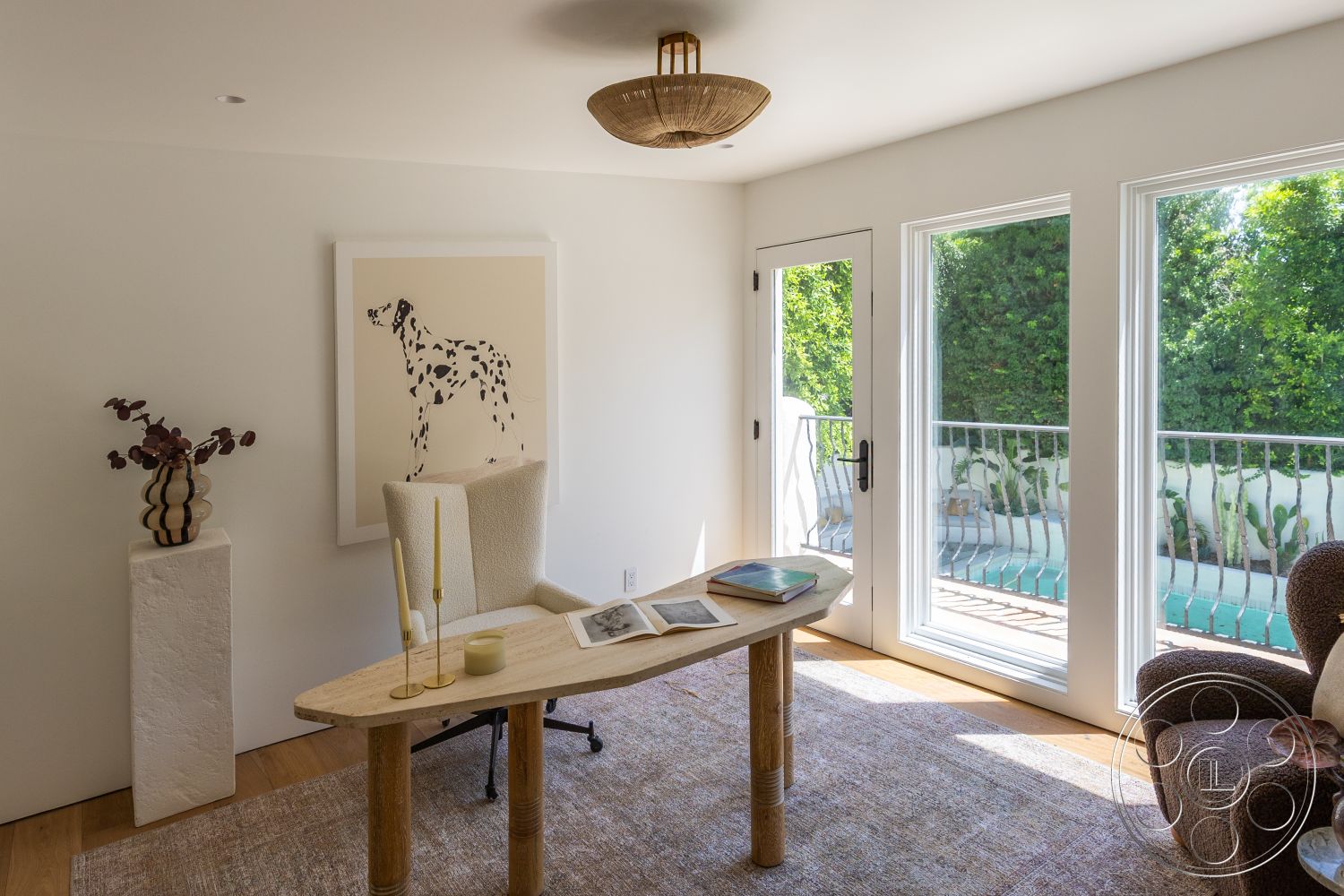 Medit 168 - exterior view, woven area rug, textured plaster walls, large floor-to-ceiling windows, natural wood floors, modern armchair, interior office space, contemporary light fixture, balcony railing, wooden table legs, modern desk with rounded edges, open door to outdoor space, decorative vase with floral arrangement, abstract dog art on wall, greenery visible outside windows