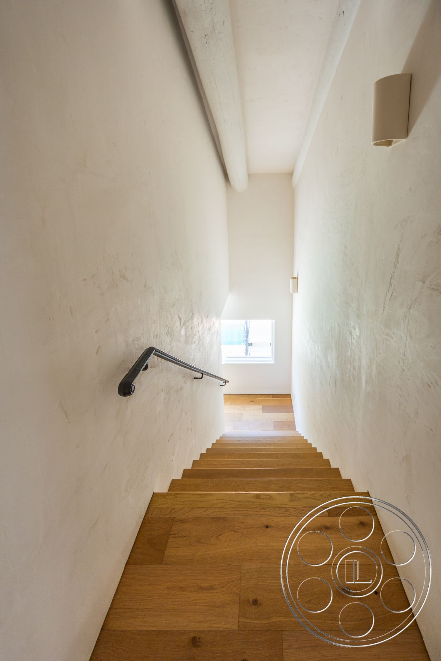 Medit 168 - exposed wood ceiling beams, large window with natural light, textured plaster wall finish, metal stair railing, hardwood stair flooring, light-filled stairwell