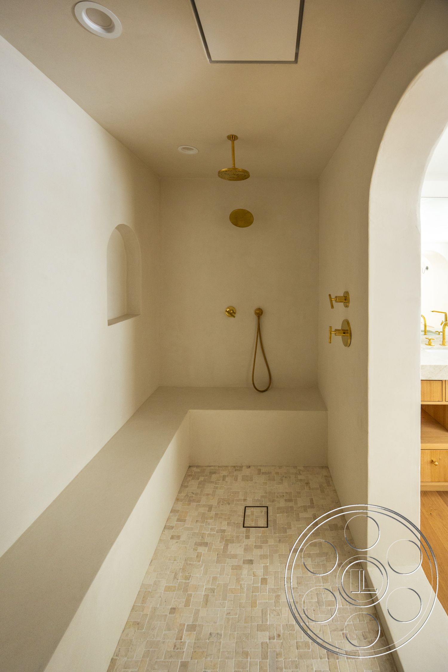 Medit 168 - neutral color palette, recessed lighting, minimalist design, built-in shower bench, textured plaster shower walls, natural stone shower flooring, brass shower fixtures, arched shower entrance, wet room layout