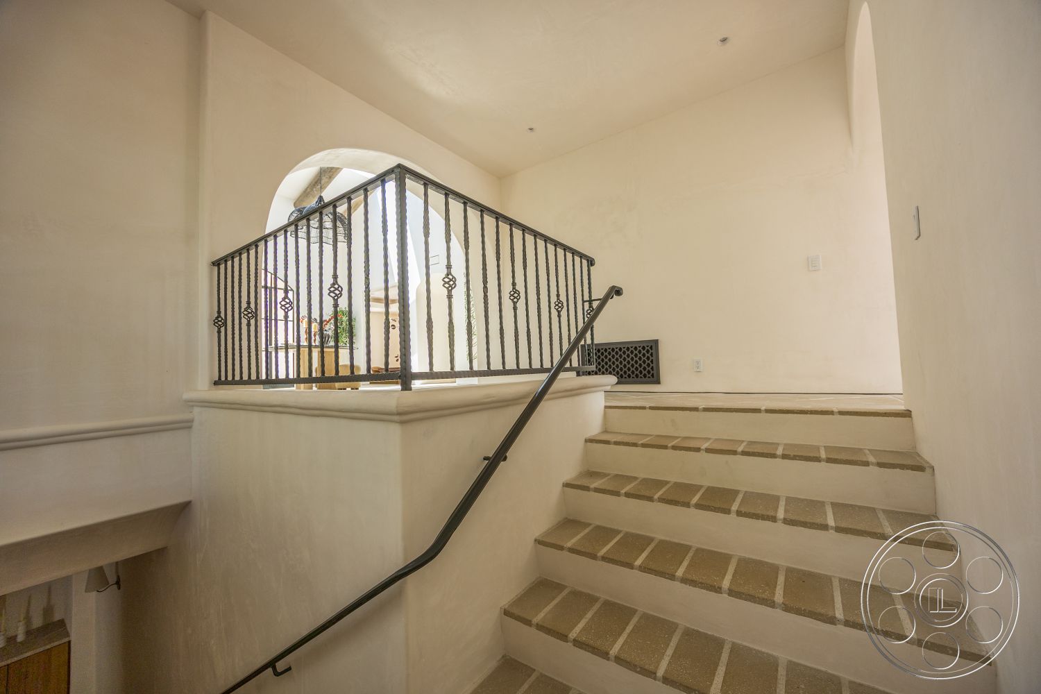 Medit 168 - vaulted ceiling, stucco walls, arched doorway, open stairwell design, terra cotta tile steps, natural light from overhead, metal railing with decorative elements, minimalist staircase design