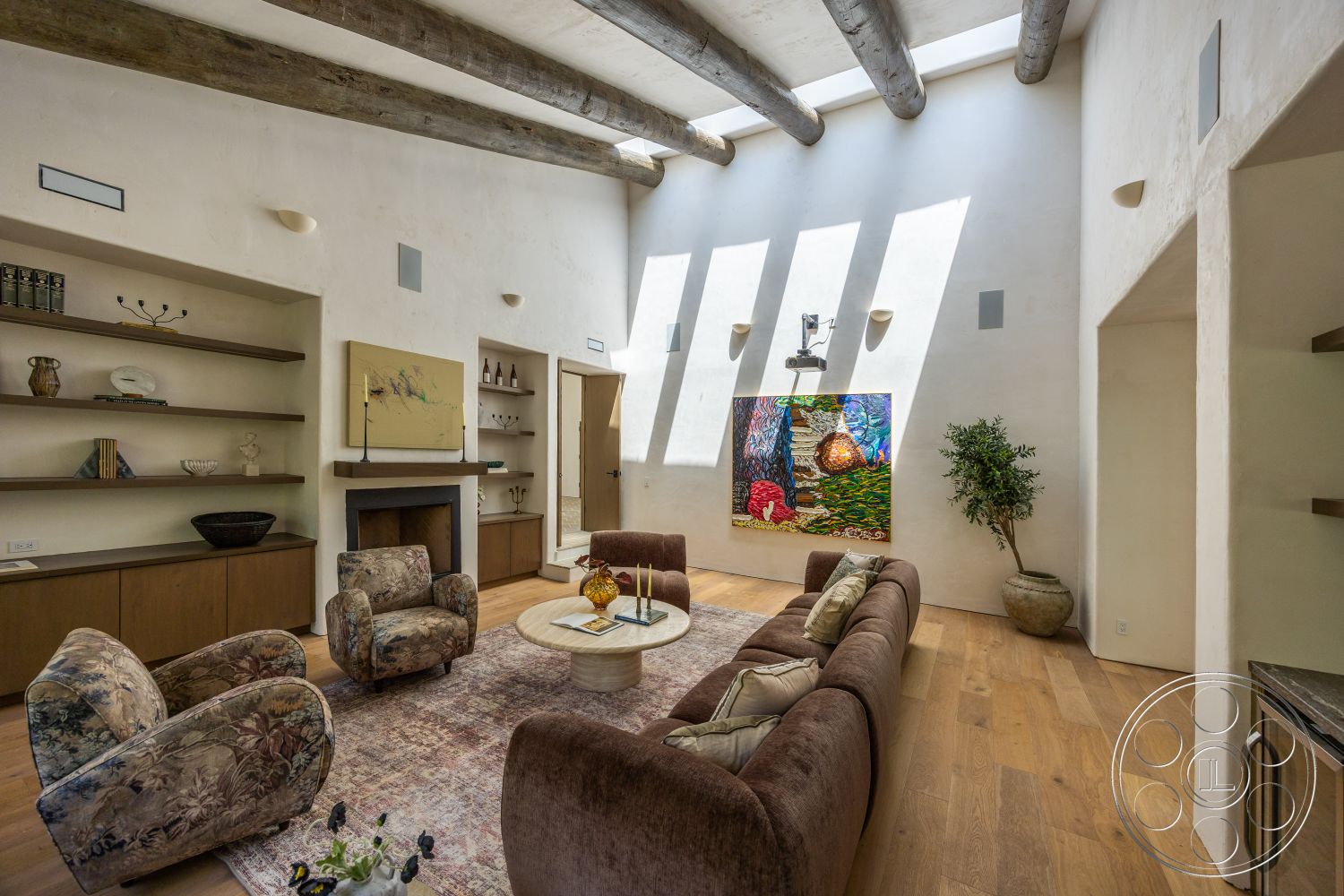 Medit 168 - artwork on wall, decorative indoor plant, textured plaster walls, round wooden coffee table, exposed wood ceiling beams, hardwood living room floors, natural light from skylights, vaulted living room ceiling, built-in wooden shelves, contemporary seating arrangement