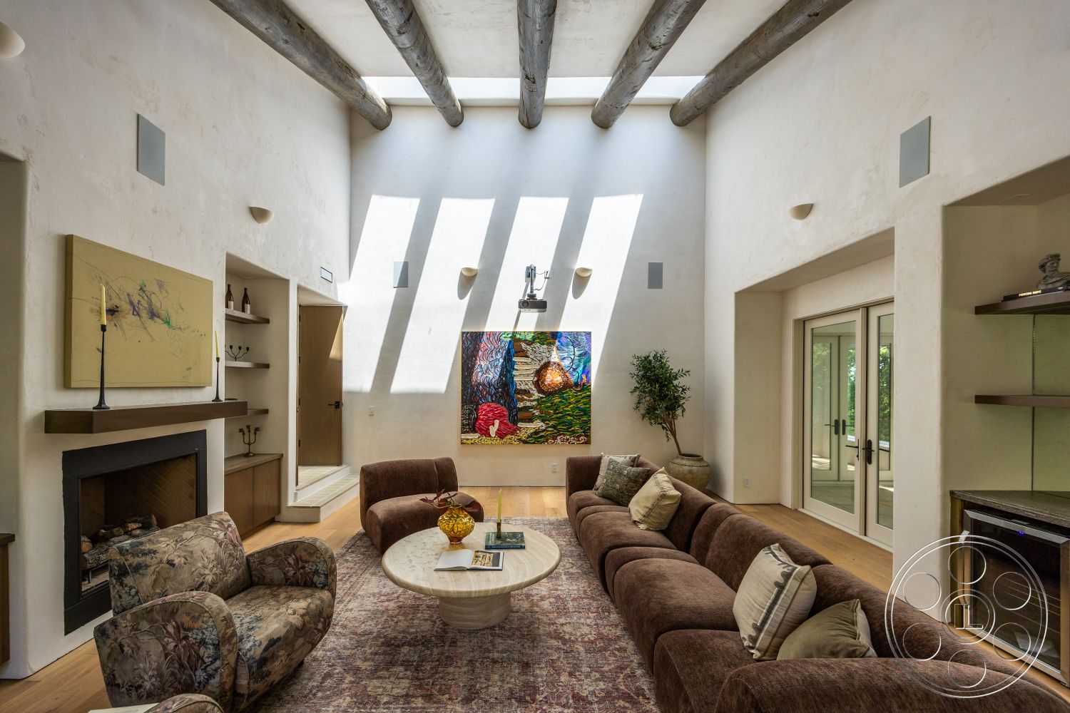 Medit 168 - round coffee table, artwork display, floor-to-ceiling windows, textured plaster walls, exposed wood ceiling beams, hardwood living room floors, natural light from skylights, modern sectional sofa, built-in shelving unit, painted accent wall, contemporary fireplace surround