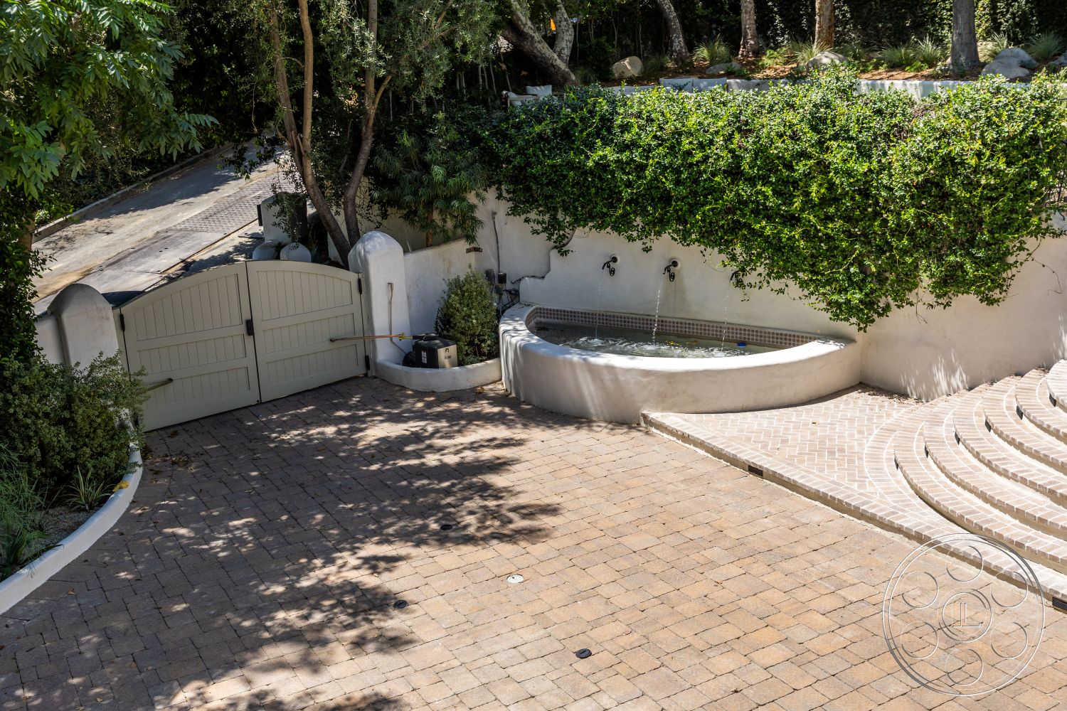 Medit 168 - paver driveway, outdoor seating area, stepping stone pathway, stucco wall finish, landscaped garden beds, curved patio design, natural stone landscaping, wooden double gates, exposed concrete fountain, stone wall planter, circular fountain with water feature, irregular shaped planters