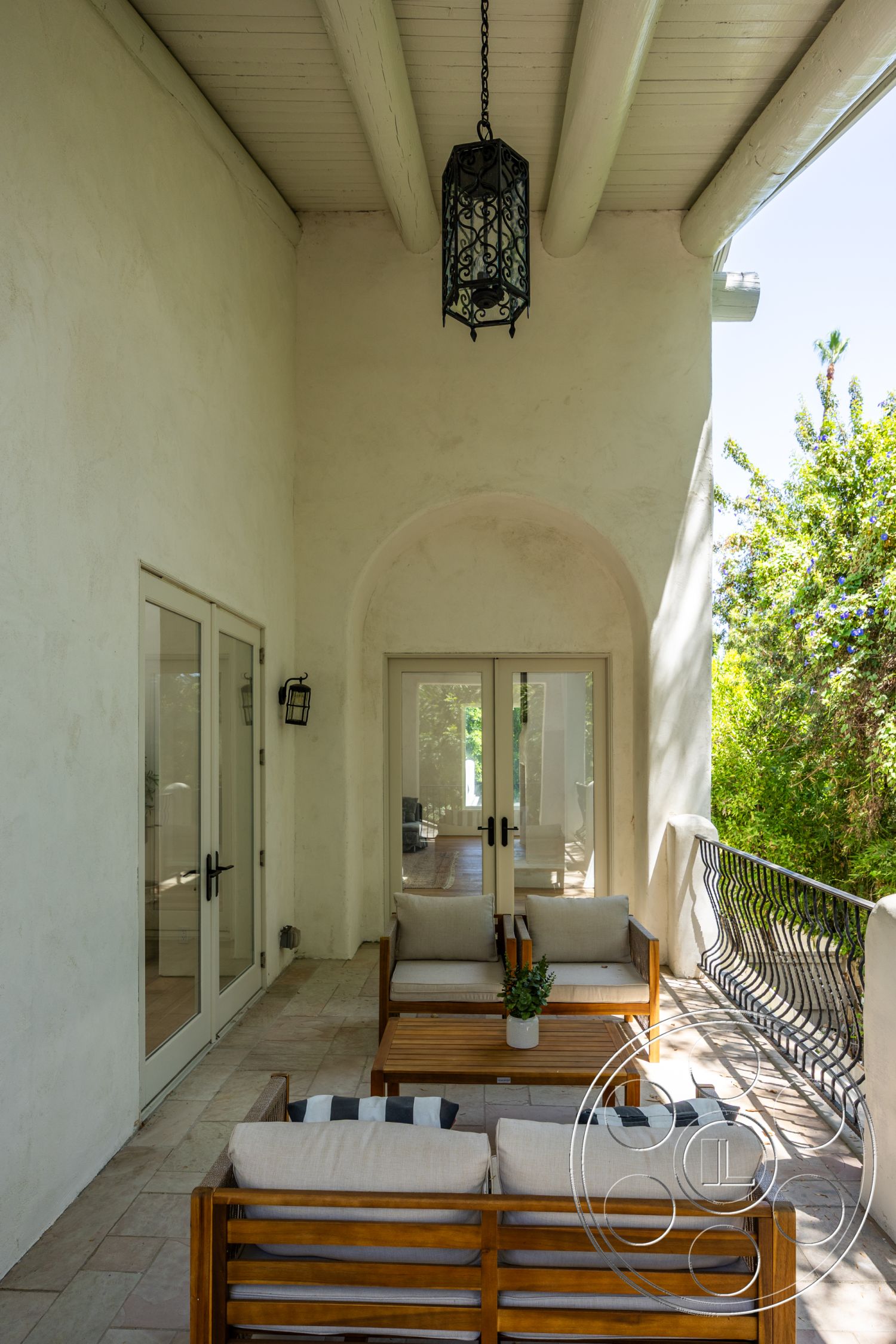 Medit 168 - exterior, green landscaping, stucco walls, arched doorways, glass patio doors, wooden outdoor furniture, decorative wrought iron railing, wood beam ceiling, natural stone floor tiles, iron lantern light fixture