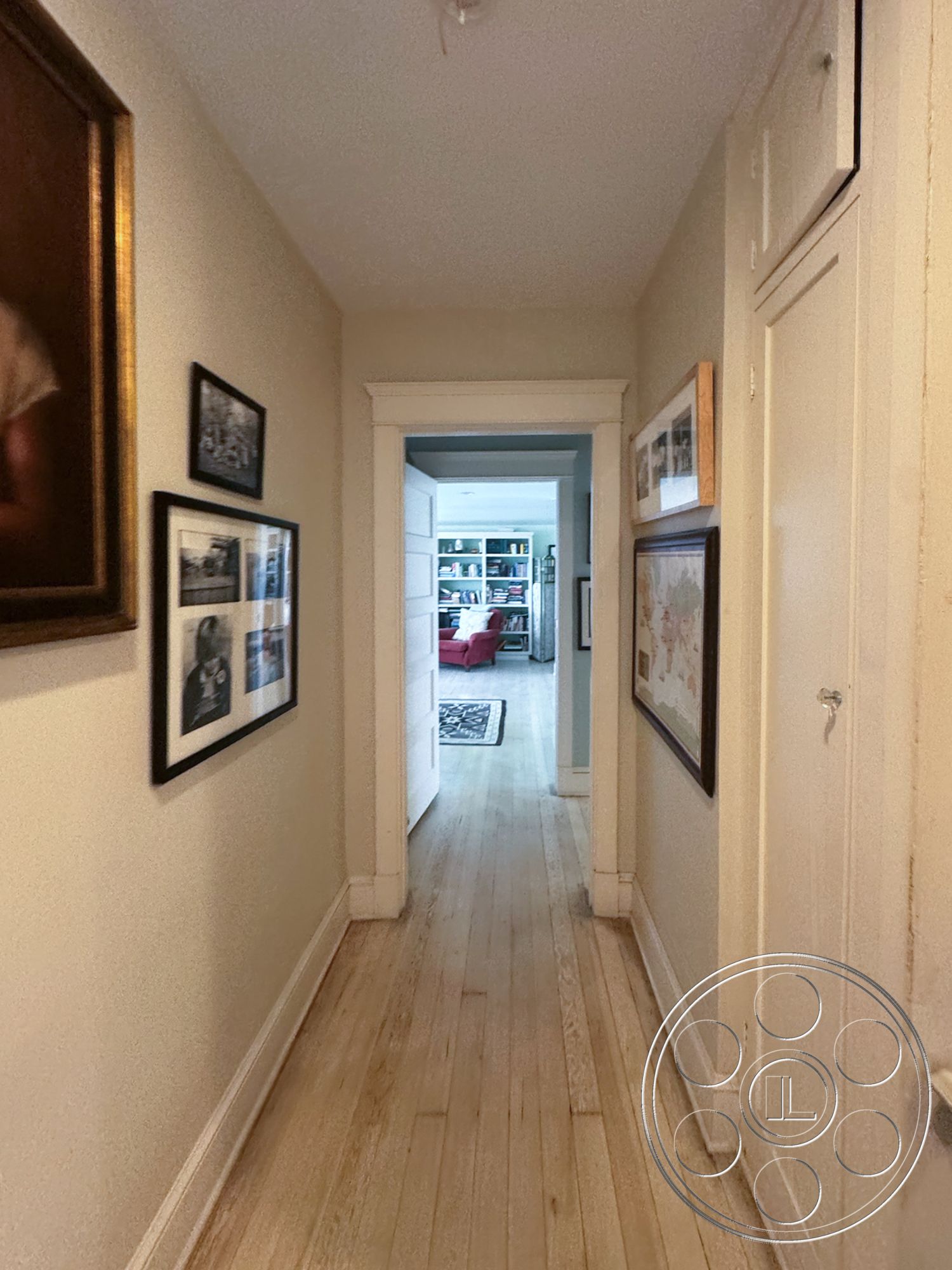 Lloyd Beach House - hardwood flooring, bright natural light, textured ceiling, open doorway, interior hallway, white painted walls, traditional door design, decorative picture frames, light wood strip flooring, frame moldings, transom above doorway