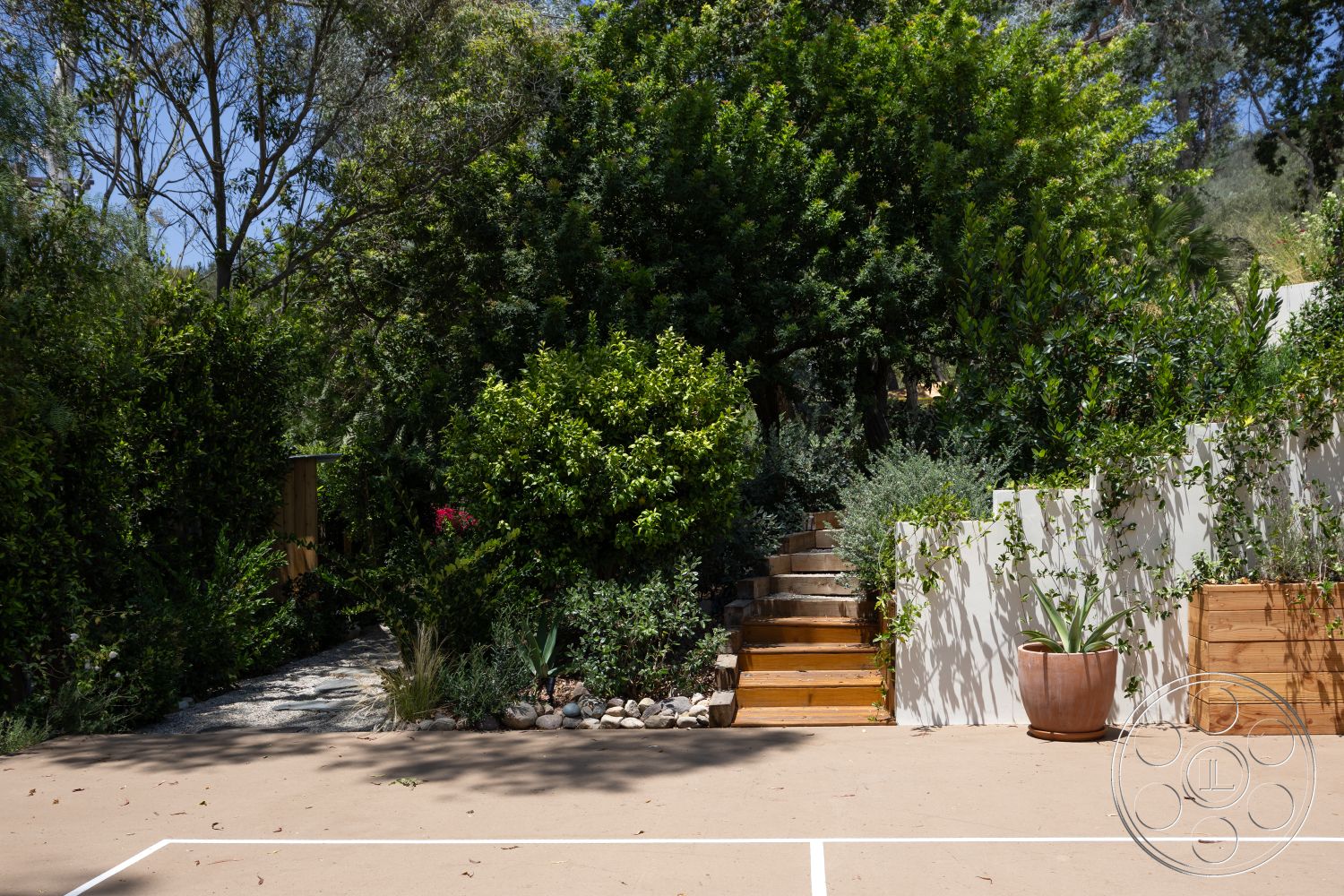 Americana 434 - exterior, green shrubs, tall trees, flowering plants, wood stairs, wooden planter, concrete patio floor, stone border, pathway with gravel