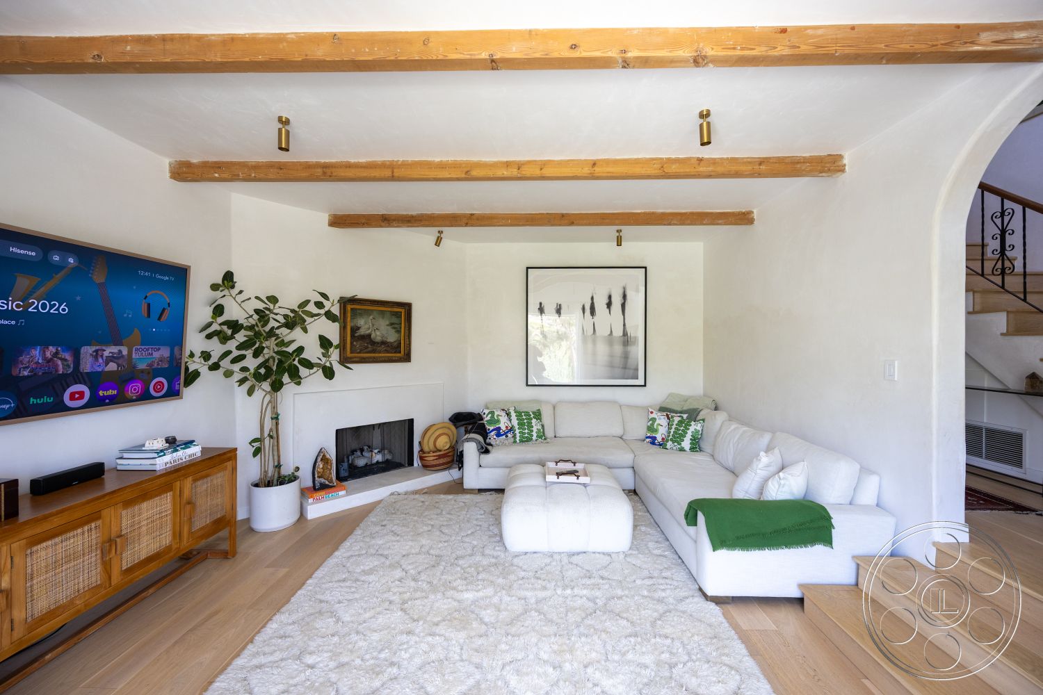 Americana 434 - neutral color palette, contemporary design, cozy atmosphere, decorative wall art, textured plaster walls, arched doorway, white sectional sofa, spacious living room, comfortable seating area, exposed wood ceiling beams, hardwood living room floors, natural light interior, wood beam ceiling, stone fireplace surround, modern entertainment center, indoor plant decoration, green accent throw