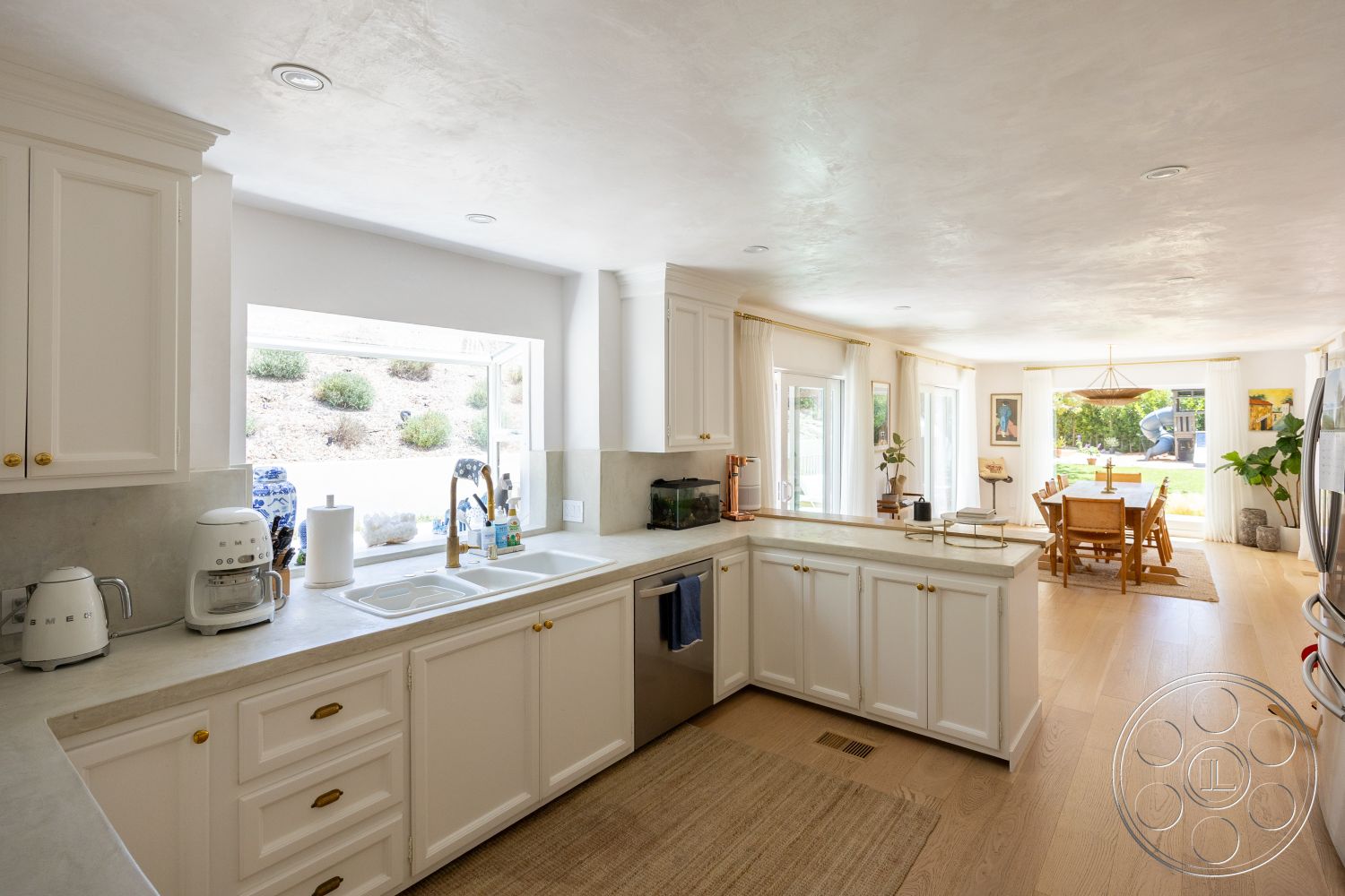 Americana 434 - minimalist decor, neutral color palette, natural light, stainless steel appliances, open concept layout, concrete countertops, round dining table, recessed ceiling lights, hardwood kitchen floors, attached outdoor patio area, white painted kitchen cabinets, large kitchen window