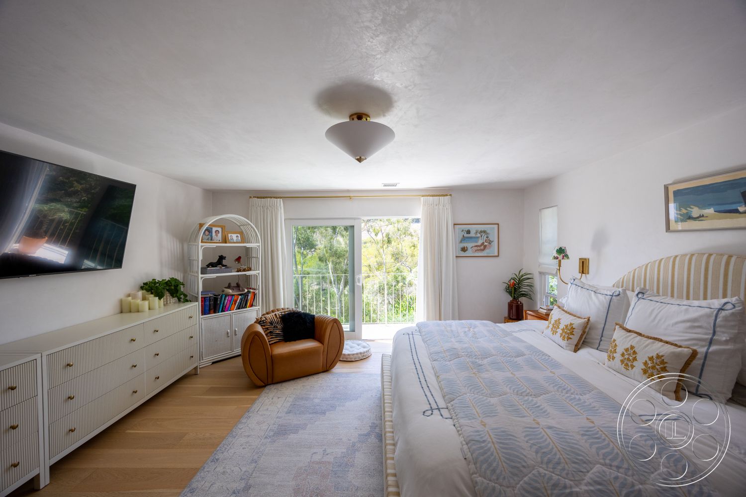 Americana 434 - natural light, floor-to-ceiling windows, textured plaster walls, glass sliding door, hardwood bedroom floors, white painted walls, decorative indoor plants, framed artwork on walls, modern upholstered bed, bohemian area rug, minimalist shelving unit, wooden dresser with horizontal slats, overhead pendant light fixture, cozy reading nook with accent chair