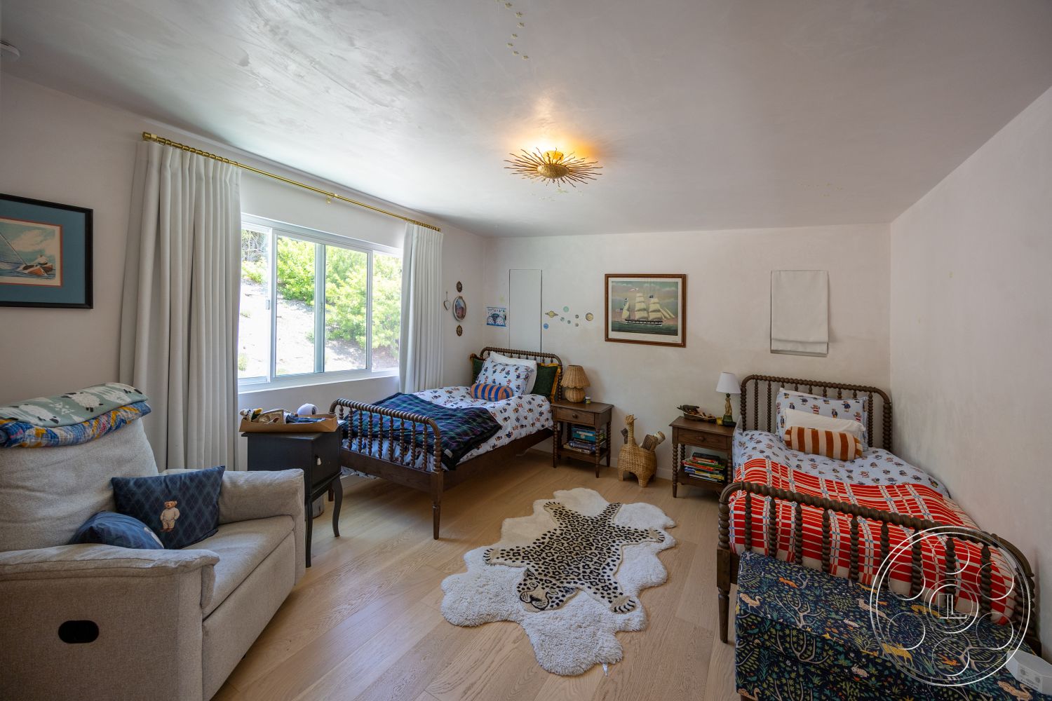 Americana 434 - white curtains, plastered walls, decorative wall accents, wooden nightstands, cowhide area rug, light hardwood bedroom floors, black framed artwork, twilight ceiling light fixture, woven wicker storage basket, twin-sized beds with decorative beddings