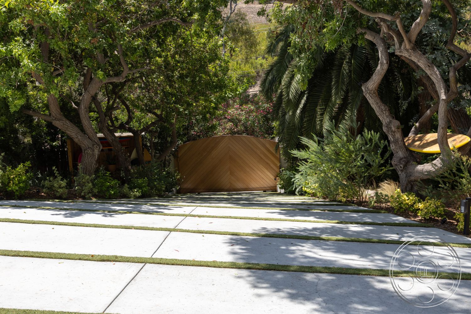 Americana 434 - exterior, landscaped garden, lush greenery, palm trees, vertical wood slats, low-maintenance plants, concrete driveway, wooden gate, textured wood surface, concrete paving slabs, iron accent details, horizontal garden lines