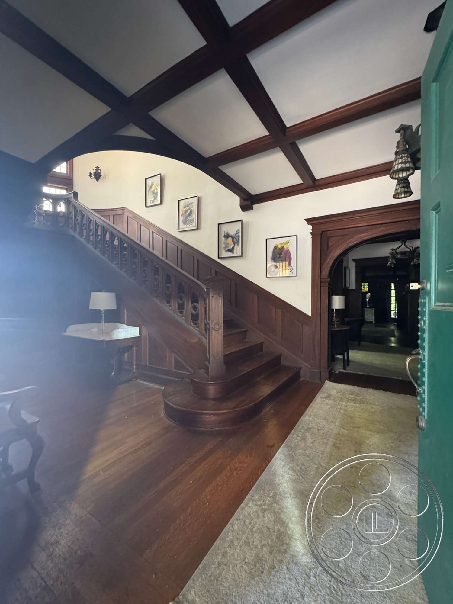 The Rosenheim Mansion - spiral staircase, framed wall art, arched doorways, ornate light fixtures, dark wood paneling, exposed wood ceiling beams, white painted walls, hardwood entryway floors, coffered ceiling details, traditional lamps