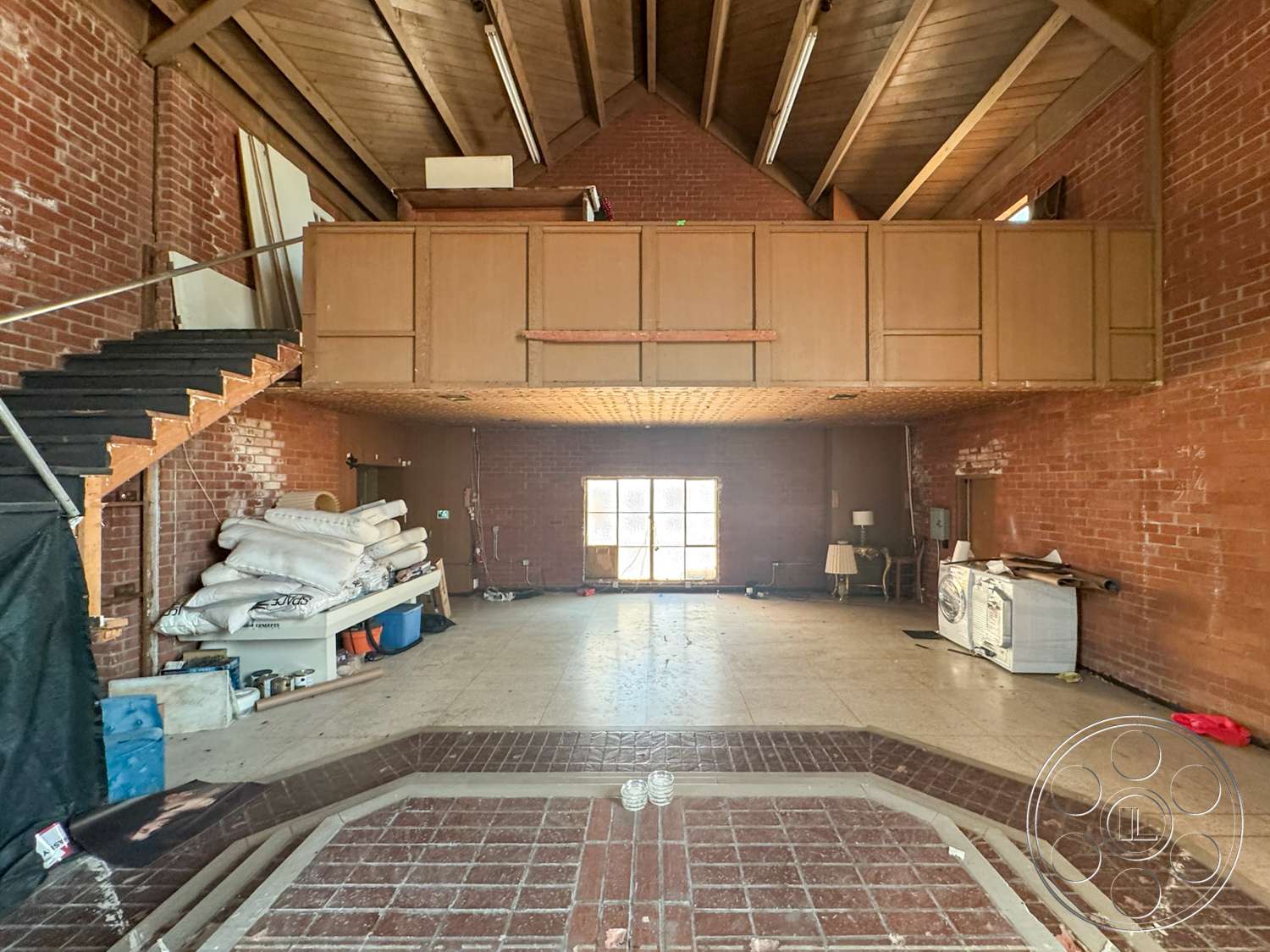 The Rosenheim Mansion - exposed brick walls, vaulted ceiling, wooden stair treads, wood beam ceiling, unfinished interior space, exposed structural beams, concrete floor tiles, functional kitchen area, open staircase with metal railings, decorative brick flooring, wooden loft area, large window with grid pattern, dialogue area with table and chairs