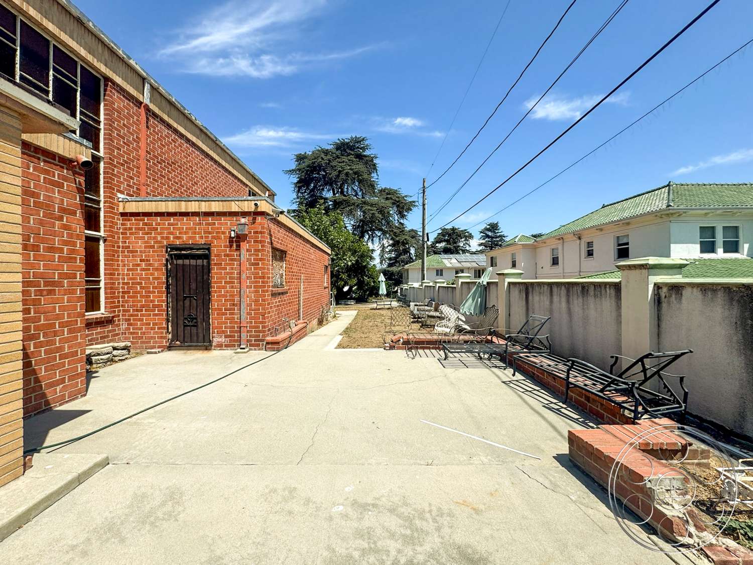 The Rosenheim Mansion - exterior, metal gate, urban environment, concrete driveway, residential setting, red brick walls, flat roof design, concrete patio floor, metal window frames, green tiled roof, stone foundation