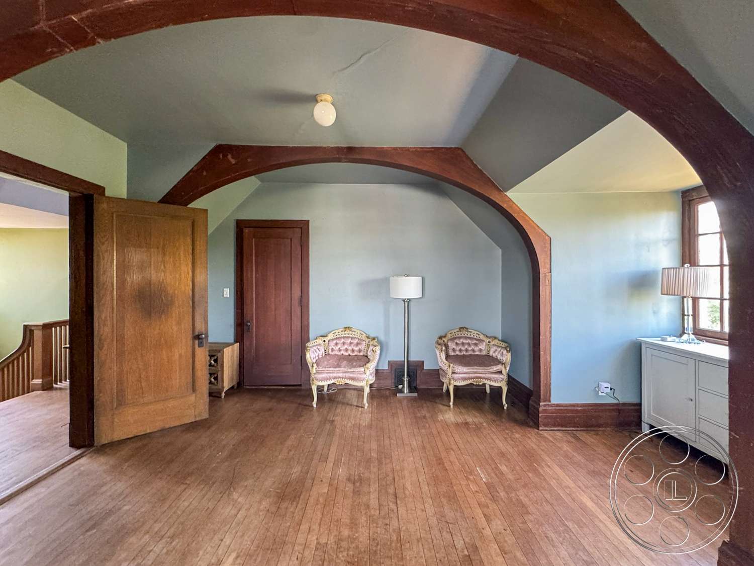 The Rosenheim Mansion - hardwood floor, built-in cabinetry, glass table lamp, exposed wood beam ceiling, wooden arched doorways, two-tone painted walls, traditional style armchairs, modern console table, large windows with wood trim