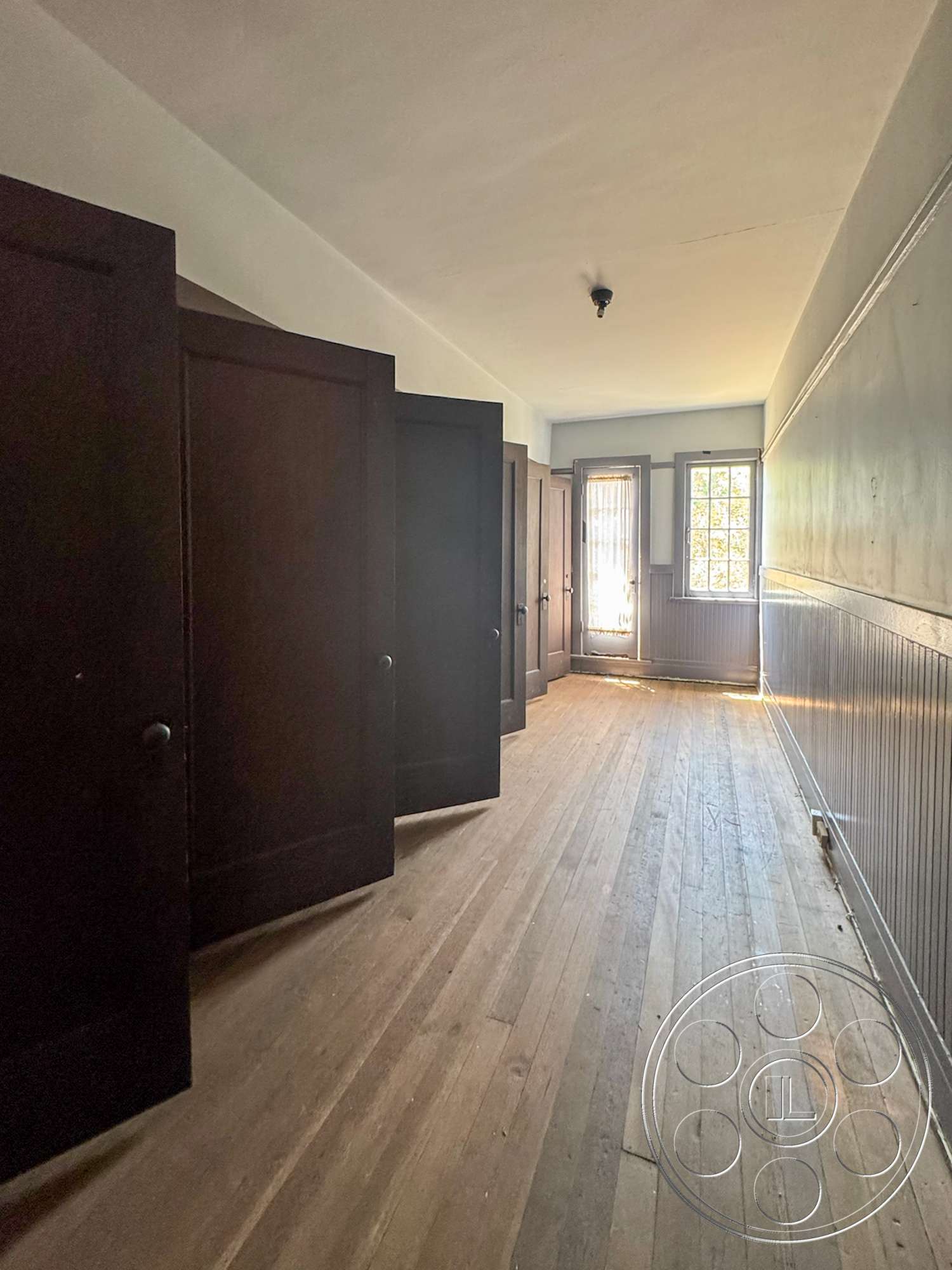 The Rosenheim Mansion - dark wood paneling, natural light from window, hardwood corridor flooring, paneled doors, historical architectural style, white plaster ceiling, doorway leading outside