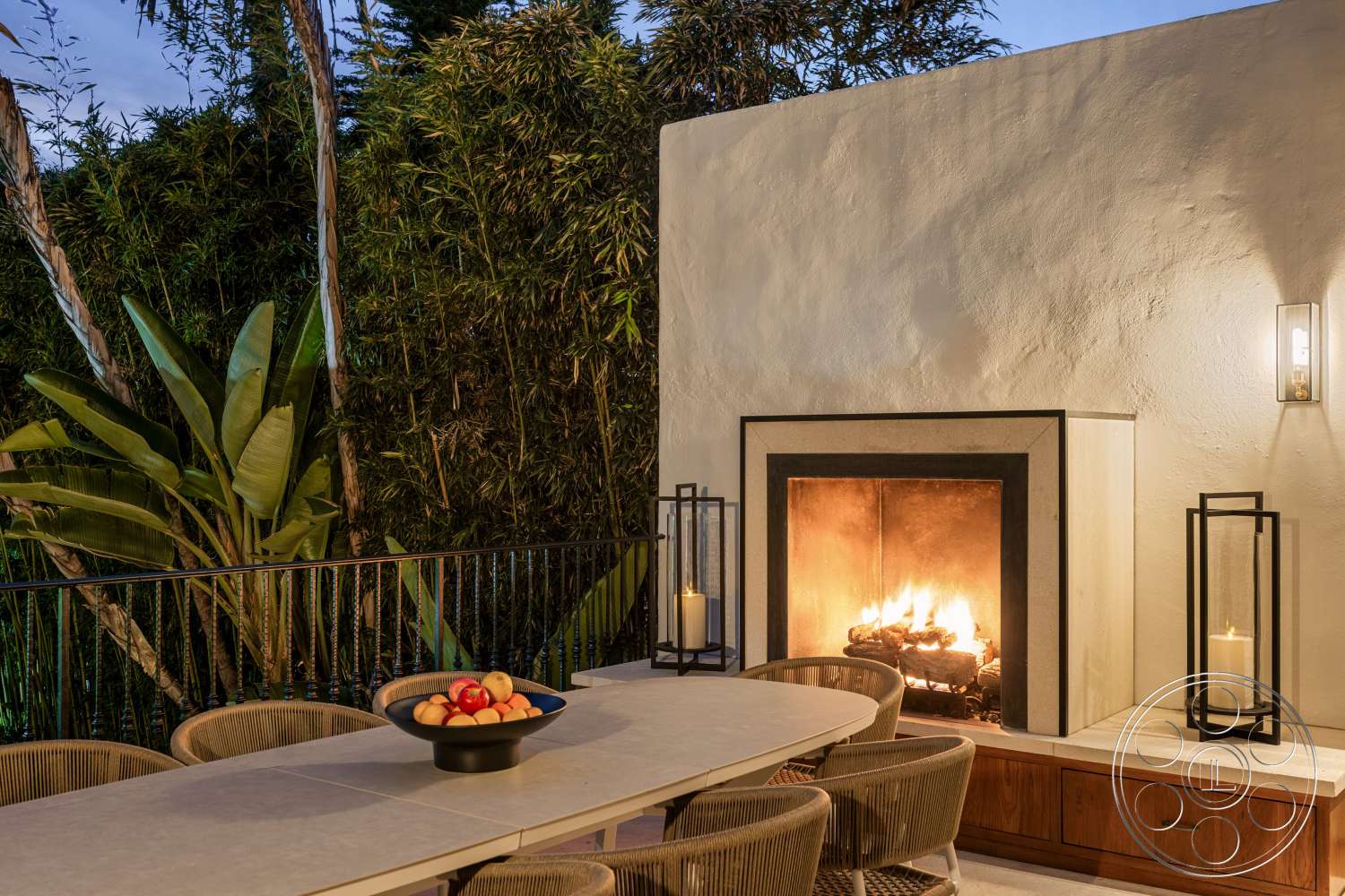 Beach 137 - exterior, wood cabinetry, black metal railing, tropical landscaping, woven outdoor chairs, ambient outdoor lighting, stucco wall finish, natural stone fireplace surround, concrete dining table, flame-lit fireplace