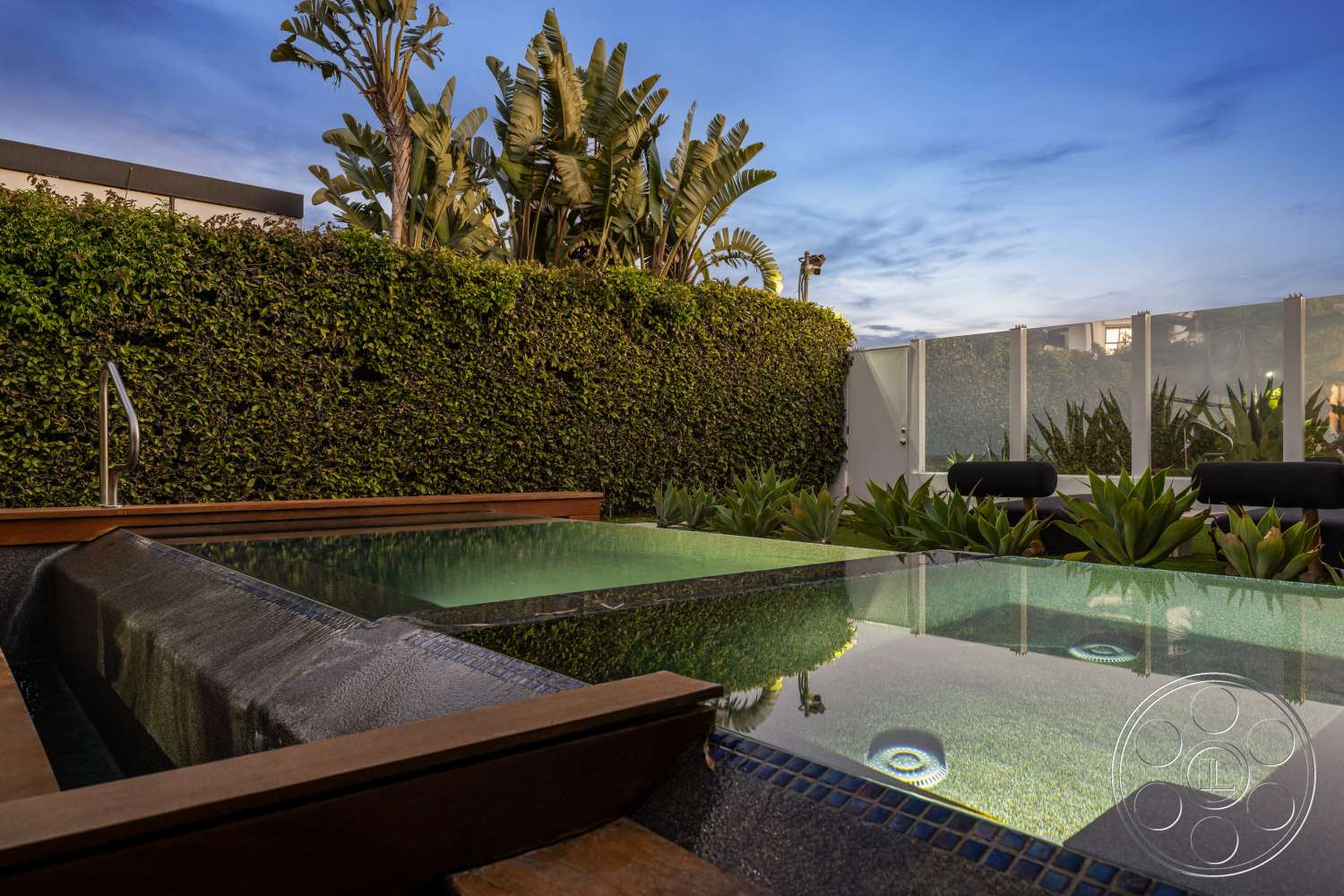 Beach 137 - nighttime ambiance, contemporary outdoor lighting, lush green landscaping, glass partition walls, built-in seating area, urban rooftop setting, tropical plant accents, tile patio flooring, outdoor spa area, wooden hot tub deck, stone wall surround, modern rectangular hot tub