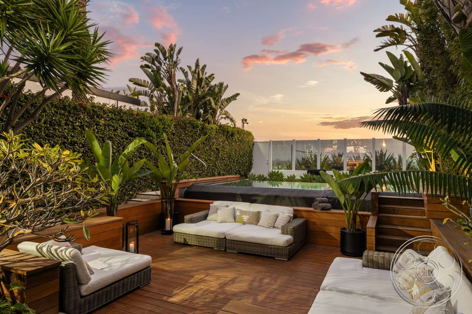 Beach 137 - exterior, wooden planter boxes, modern outdoor seating, wooden deck flooring, rectangular infinity pool, potted tropical plants, glass pool barrier, contemporary landscape design, green hedge privacy wall, sunset skyline view