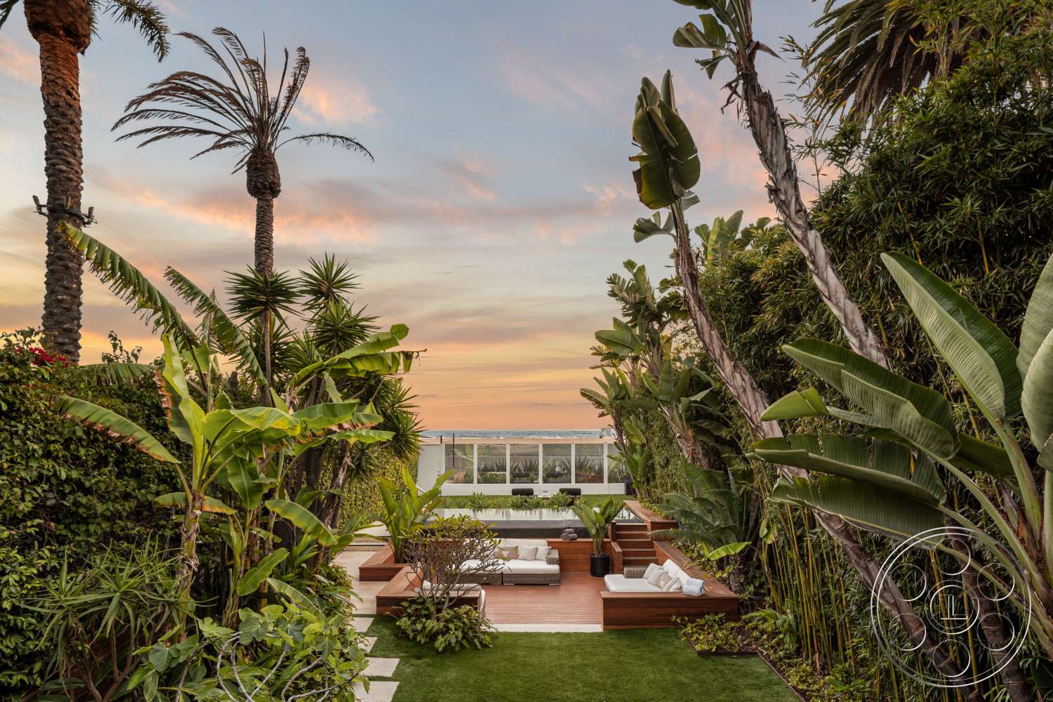 Beach 137 - exterior, modern outdoor furniture, concrete stepping stones, panoramic ocean view, lush green foliage, artificial grass lawn, tropical landscaping with palm trees, wood deck seating area, sunset sky backdrop, wood steps leading to deck