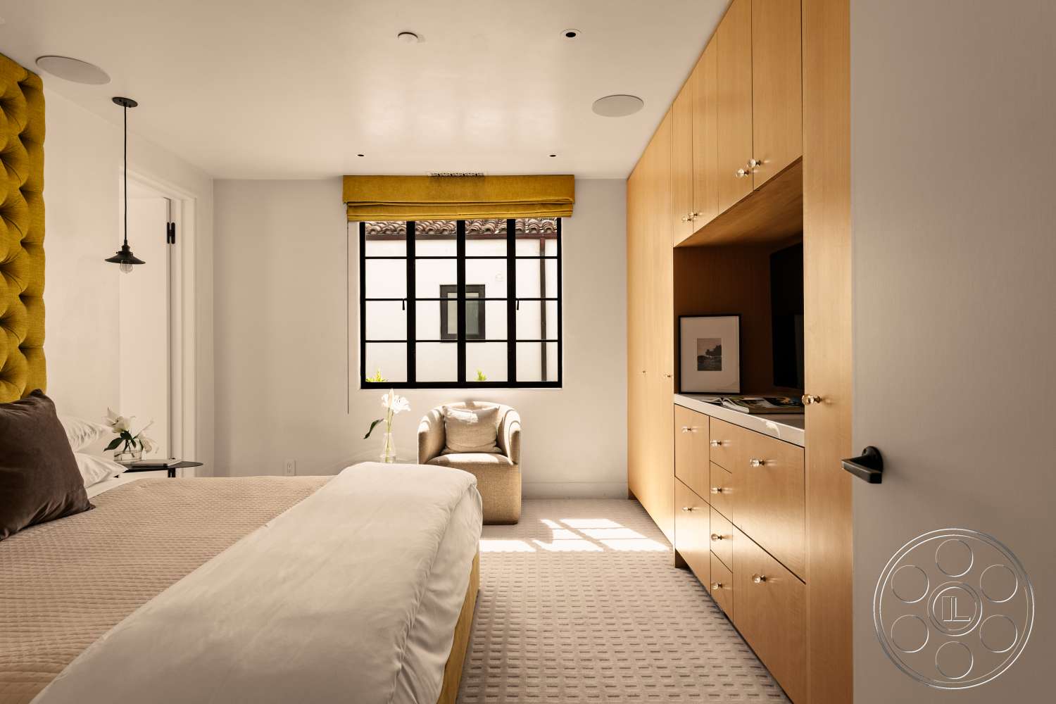 Beach 137 - modern pendant lighting, black window frames, floor-to-ceiling window, decorative armchair, simple bedside table, interior bedroom, white painted walls, carpet bedroom flooring, black door hardware, tufted yellow headboard, hardwood cabinetry, textured cream bedding, dark upholstered accent pillows, yellow window treatment