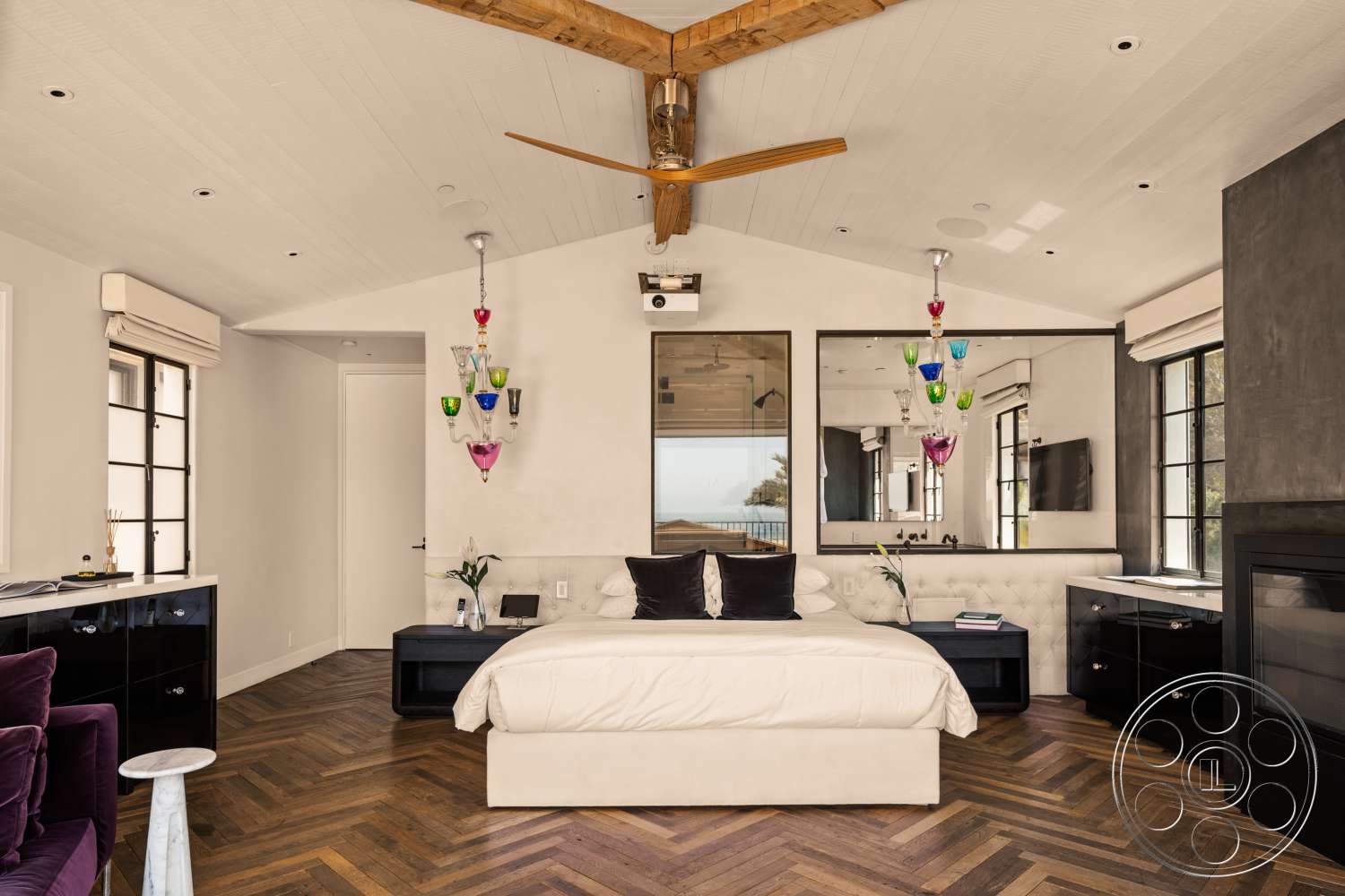 Beach 137 - large floor-to-ceiling windows, neutral color scheme, contemporary decor style, textured plaster wall, vaulted ceiling with exposed wood beams, modern fireplace surround, built-in shelving unit, herringbone hardwood bedroom floors, black cabinetry with polished hardware, colorful glass pendant light fixtures, tufted upholstered bed base