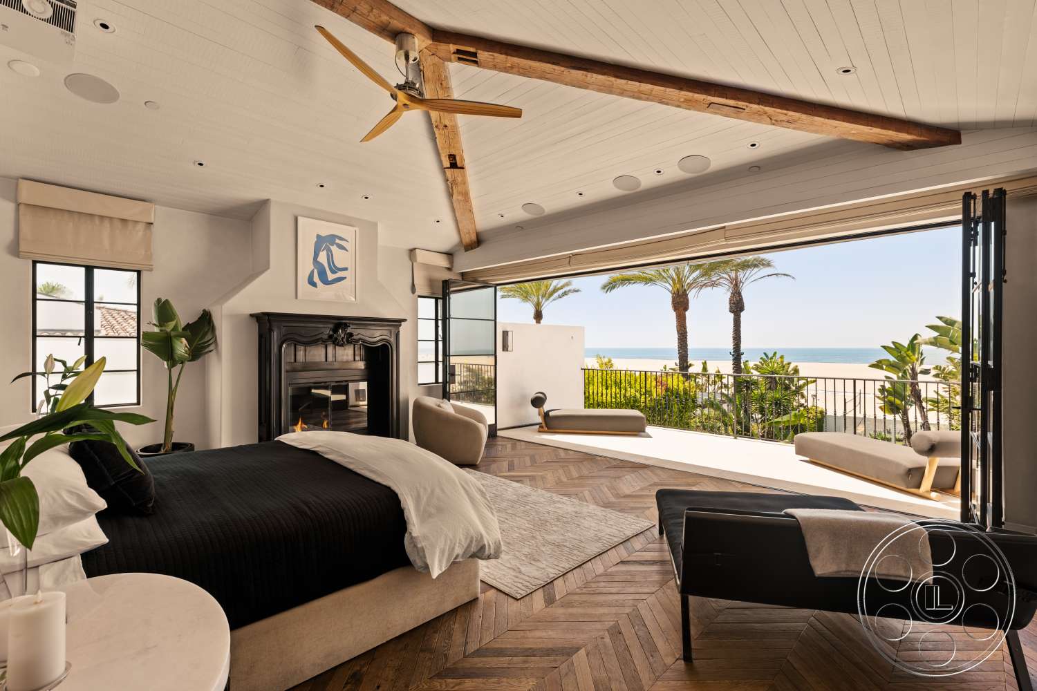 Beach 137 - neutral color palette, contemporary artwork, floor-to-ceiling windows, cozy reading nook, plush seating area, modern minimalist decor, palm tree view, exposed wood ceiling beams, natural light flooding in, black fireplace surround, beachfront setting, decorative house plants, hardwood chevron pattern flooring, king-sized bed with black bedding, sliding glass door to patio