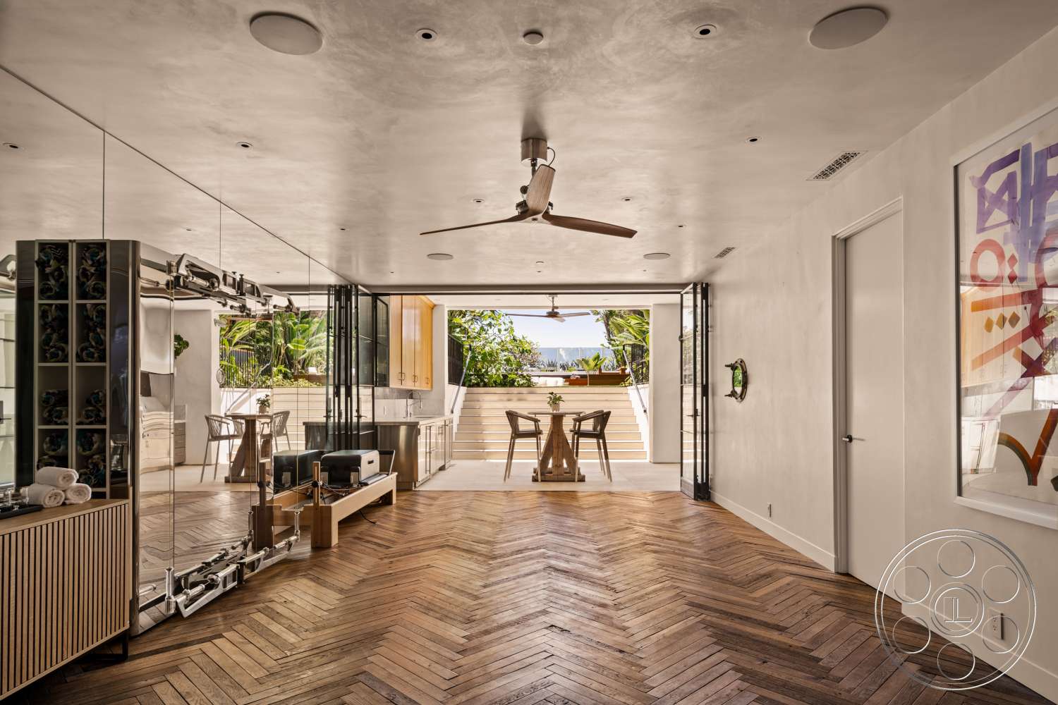 Beach 137 - neutral color palette, natural light, open floor plan, ceiling fan, light wood cabinetry, artwork on wall, herringbone wood flooring, black framed glass doors, outdoor patio view, glass wall partition, decorative wall mirror, smooth plaster ceiling, modern minimalist furnishings