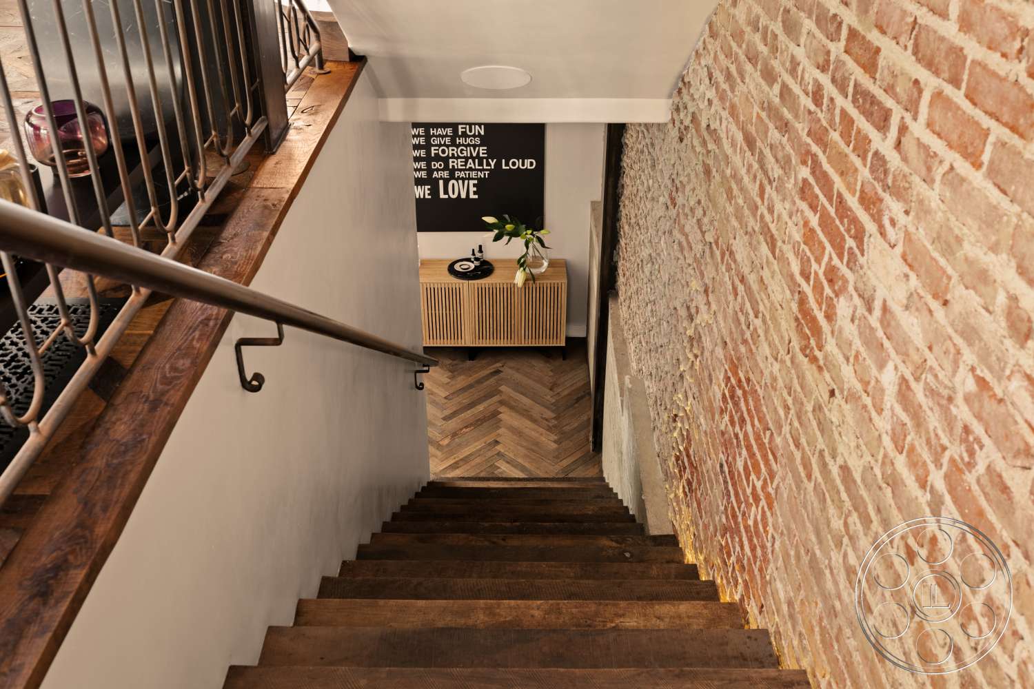 Beach 137 - minimalist decor, natural light, modern entryway, metal railing, decorative planter, exposed brick wall, artwork on wall, textured wall treatment, storage cabinet, interior hallway, white painted walls, chevron hardwood flooring, hardwood stairs, contrasting materials
