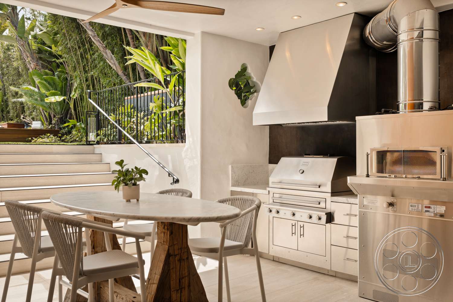Beach 137 - tile flooring, wooden dining table, metal railing, modern aesthetic, white cabinetry, concrete steps, marble countertop, open-air design, exposed ductwork, glass sliding door, woven dining chairs, interior kitchen space, stainless steel range hood, lush tropical plants, stainless steel outdoor grill, natural wood pedestal base, Oversized ceiling fan