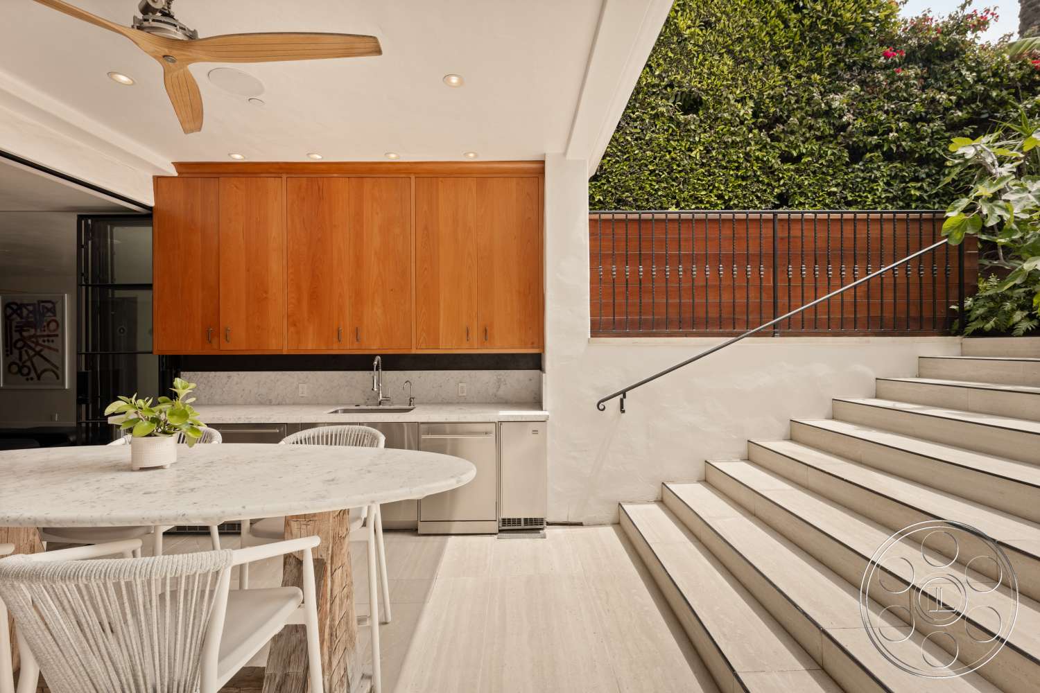 Beach 137 - natural light, minimalist design, open layout, wood cabinetry, concrete steps, marble countertop, outdoor dining space, greenery backdrop, stainless steel refrigerator, modern ceiling fan, large format tile flooring, textured wall detailing, exterior kitchen area, white cushioned dining chairs, linear railing