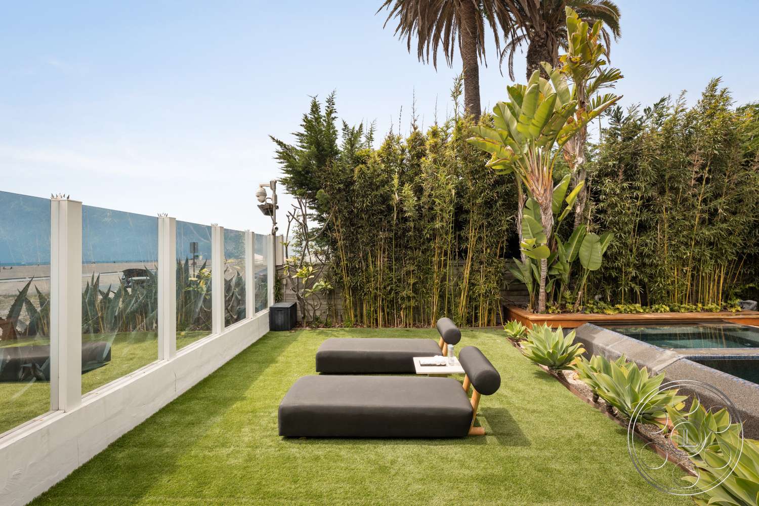 Beach 137 - exterior, palm trees, wooden planter boxes, tropical landscaping, glass pool fence, modern lounge chairs, artificial grass lawn, concrete pool edge, succulent plant arrangements