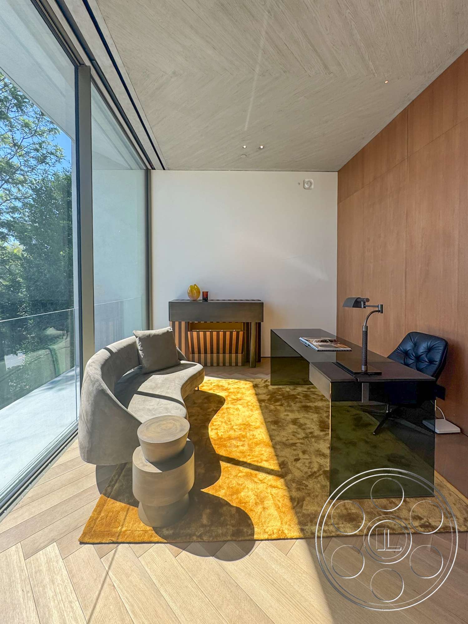 Modern 516 - modern lighting fixtures, floor-to-ceiling windows, round wooden side table, wood panel accent wall, textured concrete ceiling, gray upholstered sofa, light wood herringbone flooring, black lacquered desk, orange area rug