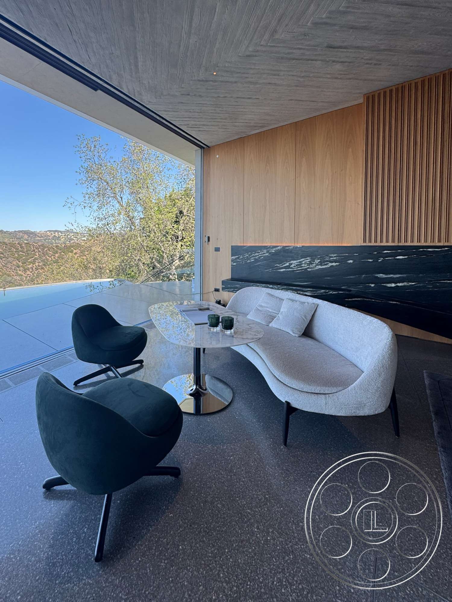 Modern 516 - polished concrete flooring, floor-to-ceiling windows, textured wood ceiling, chrome accent table, black marble feature wall, mountain view setting, open concept living area, walnut wood paneling, modern curved sofa, elegant contemporary design