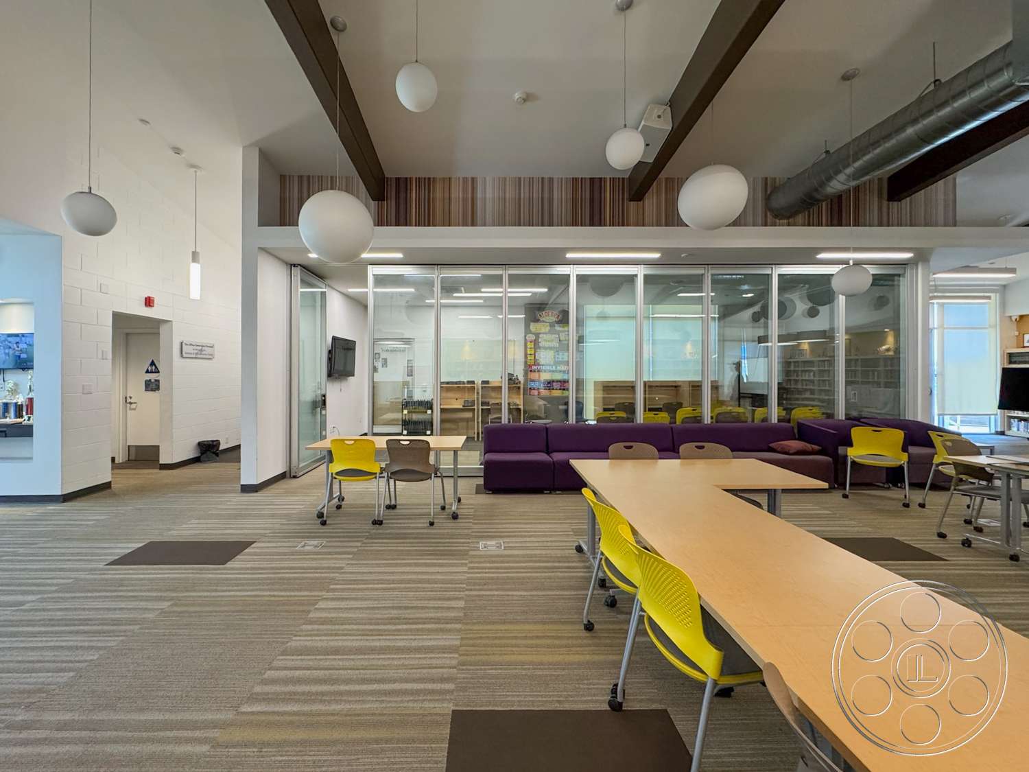 School 20 - floor-to-ceiling windows, textured wall panels, carpet flooring, linear light fixtures, yellow and gray color scheme, acoustic ceiling, exposed wood ceiling beams, glass partition walls, rectangular tables, polypropylene chair, purple sectional sofa, open collaborative space