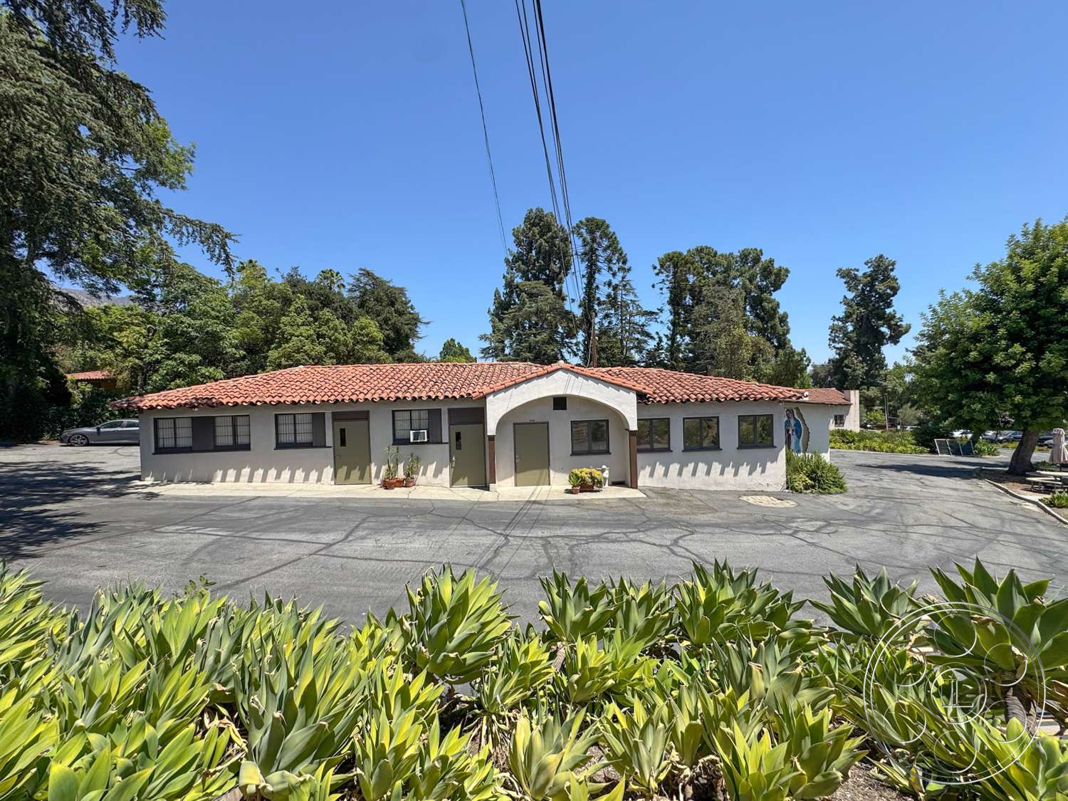 School 20 - exterior, surrounding trees, suburban setting, red tile roof, stucco walls, arched entrance, Mediterranean architectural style, concrete parking area, landscaped garden with succulents, horizontal sliding windows