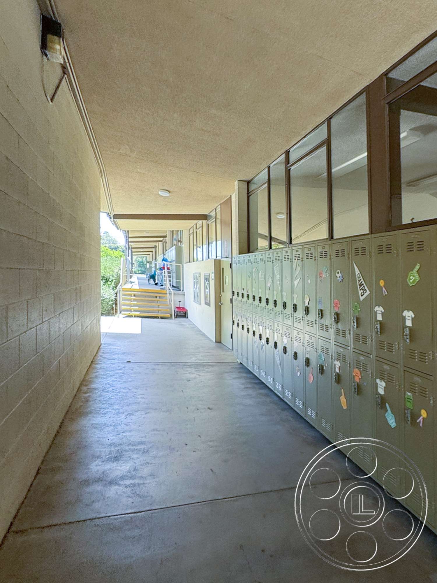 School 20 - natural lighting, concrete flooring, flat ceiling, wooden handrail, outdoor staircase, school environment, metal lockers, glass window panels, exterior corridor, cinder block walls, two-story school building