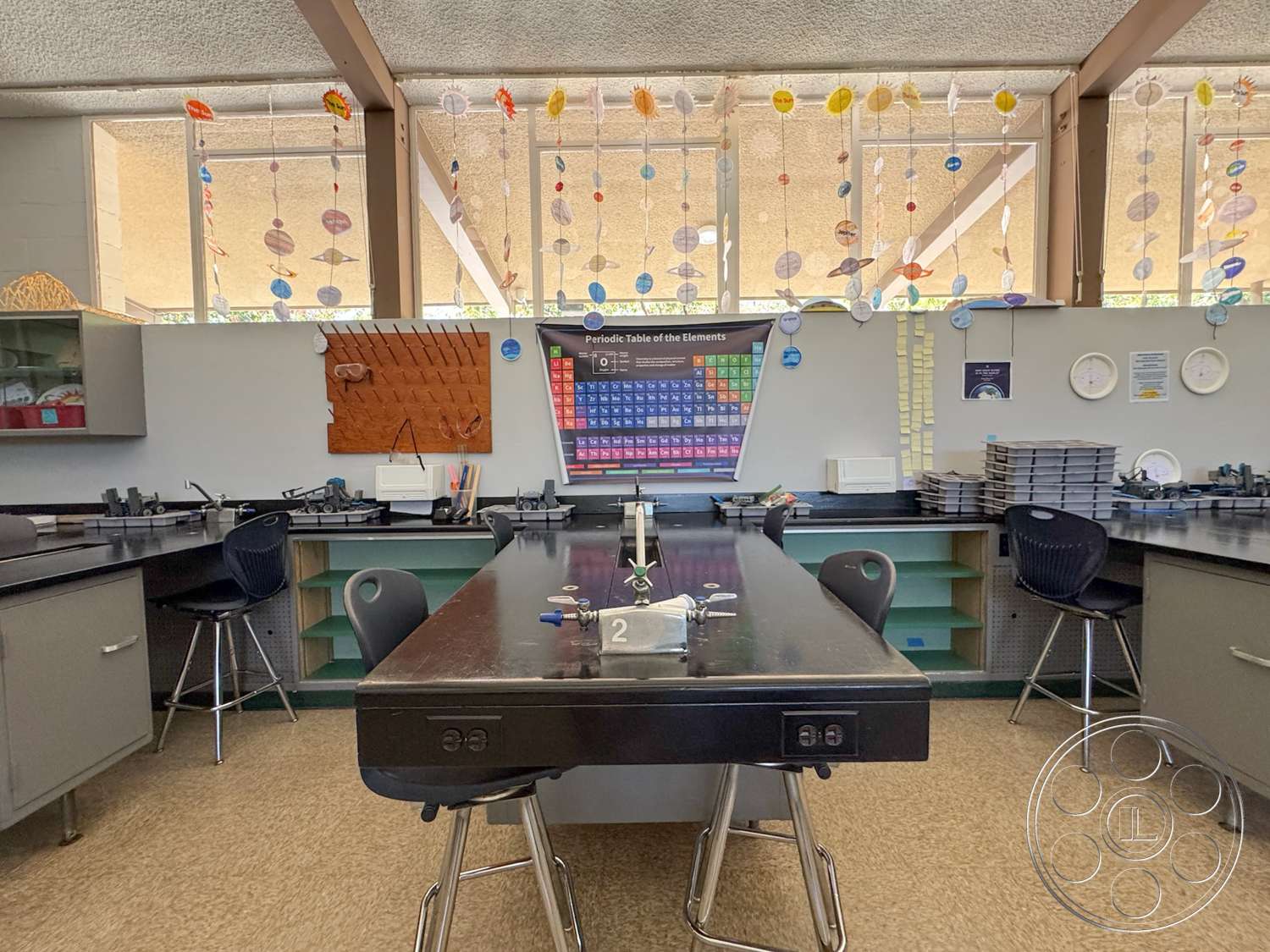 School 20 - hardwood flooring, exposed ceiling beams, acoustic ceiling tiles, built-in storage cabinets, interior laboratory space, black laminate lab countertops, floating glass ceiling panels, stainless steel lab equipment, metal lab stools, wall-mounted periodic table display, wall-mounted cork board, colorful hanging decorations