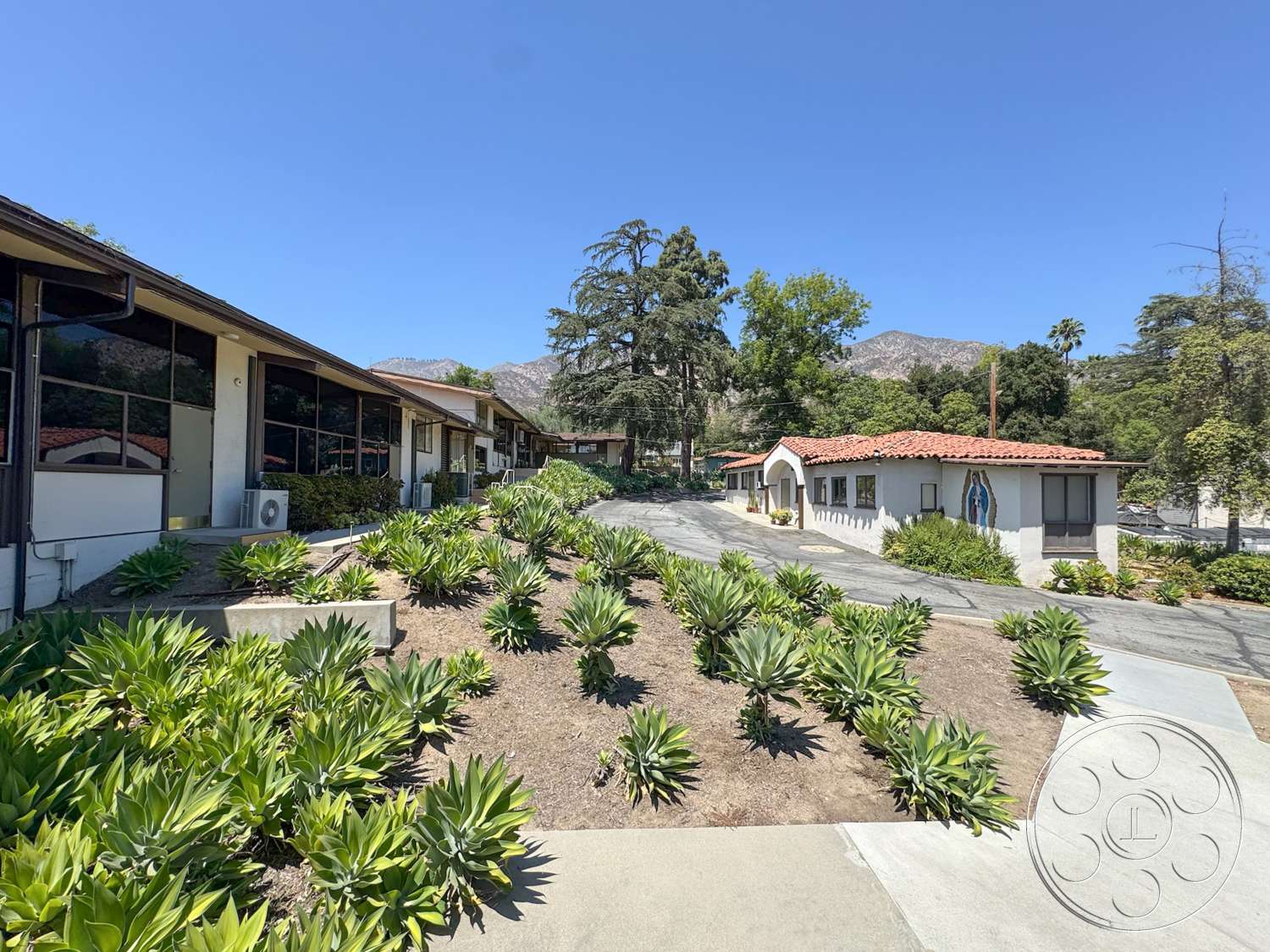 School 20 - exterior, low-maintenance plants, glass windows, mountain view, concrete walkway, desert landscaping, red tile roof, landscaped garden area, stucco building walls, angled building layout
